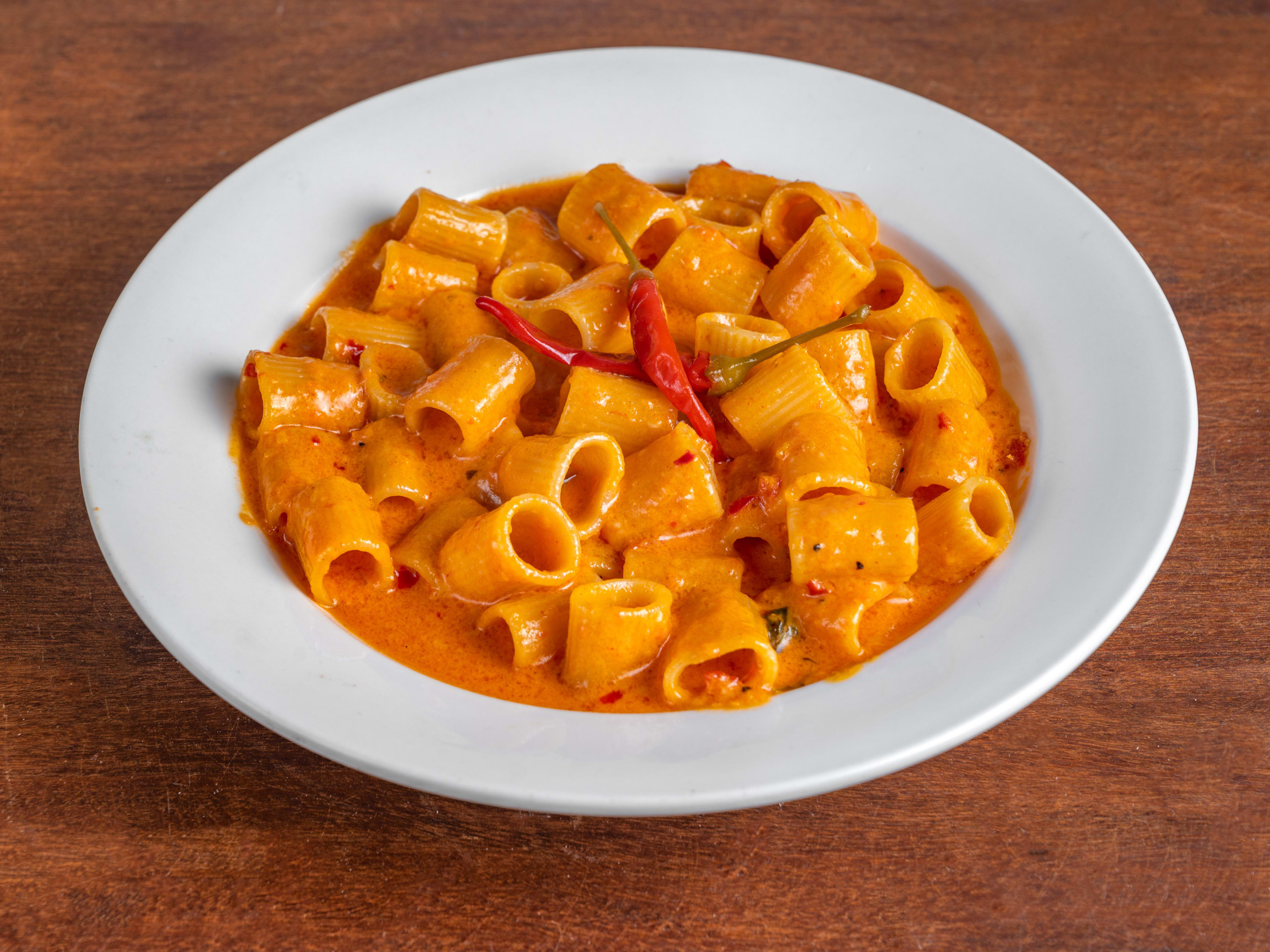 Rigatoni ala vodka with little peppers in the middle in a bowl.