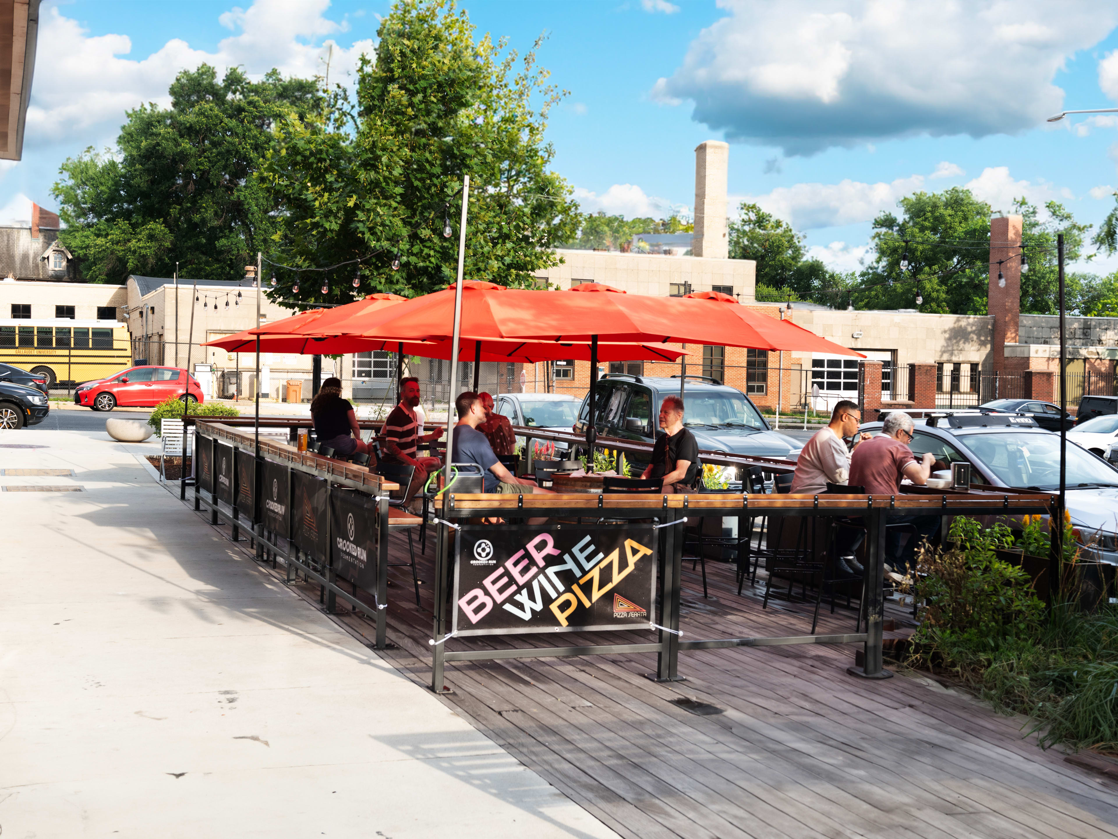 outside patio with people dining under umbrellas on a sunny day