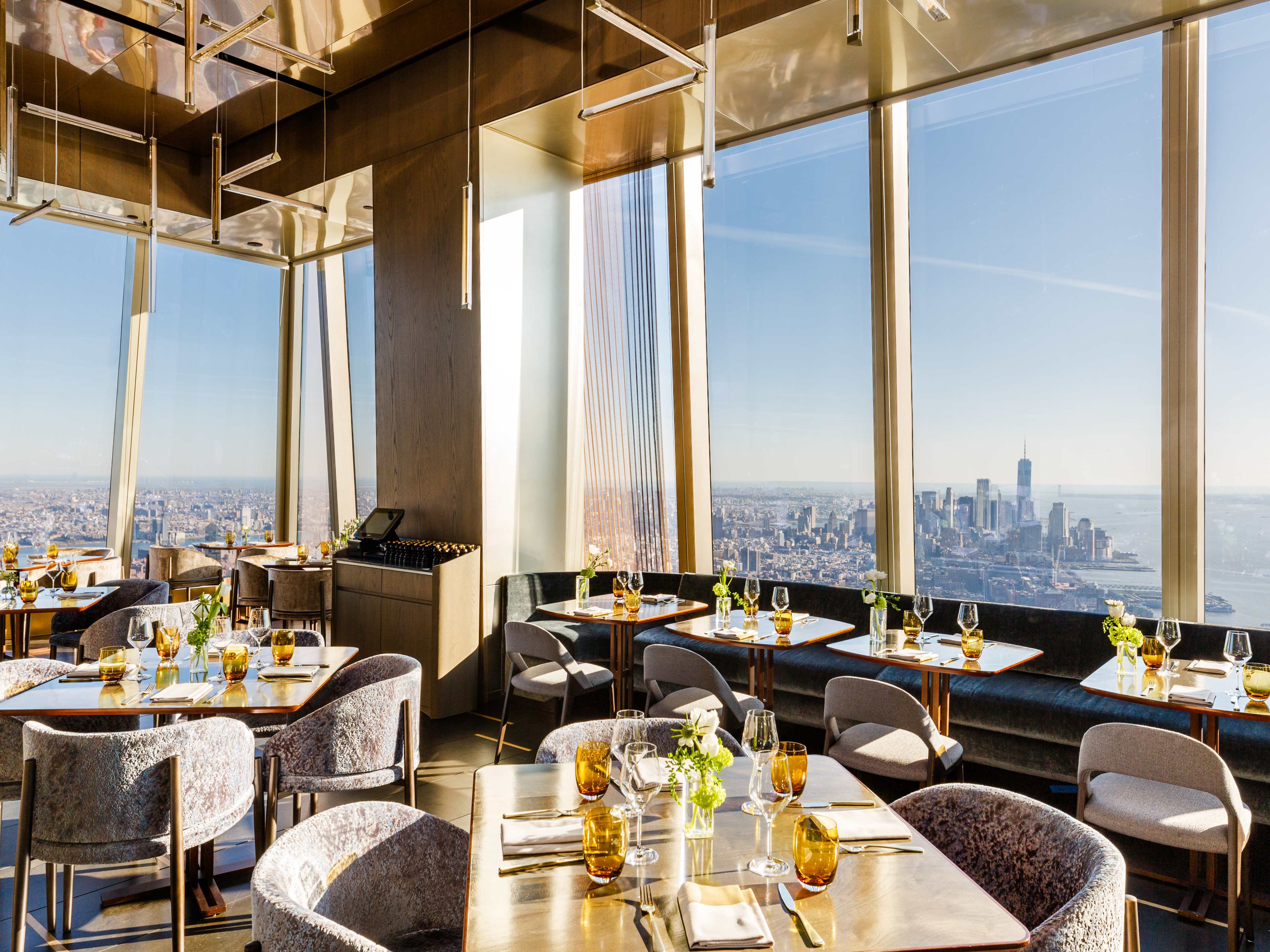 Tables next to large windows overlooking the NYC skyline at Peak.