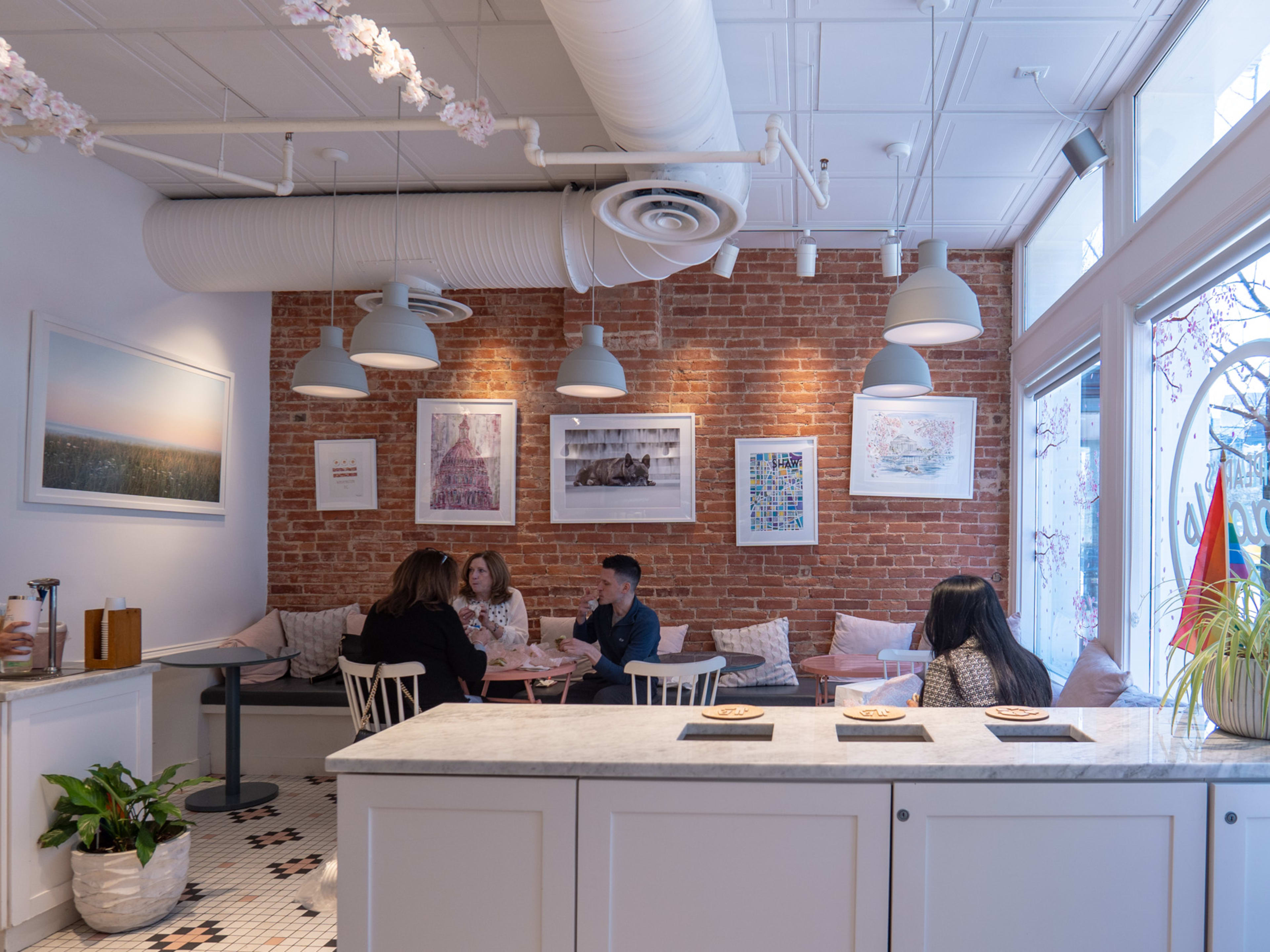 interior of bagel shop with brick wall, cozy nook seating with people eating