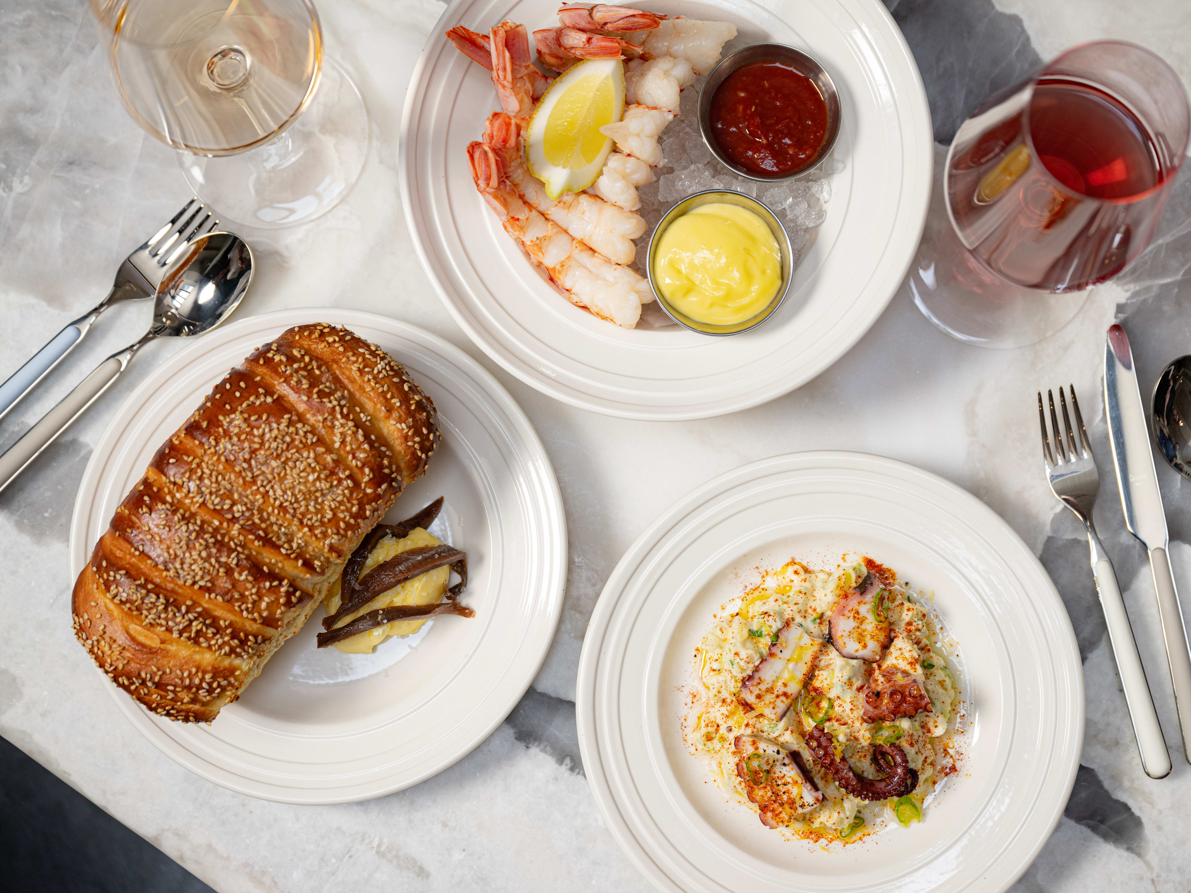 A small loaf of bread and some seafood on a table covered in a white tablecloth.