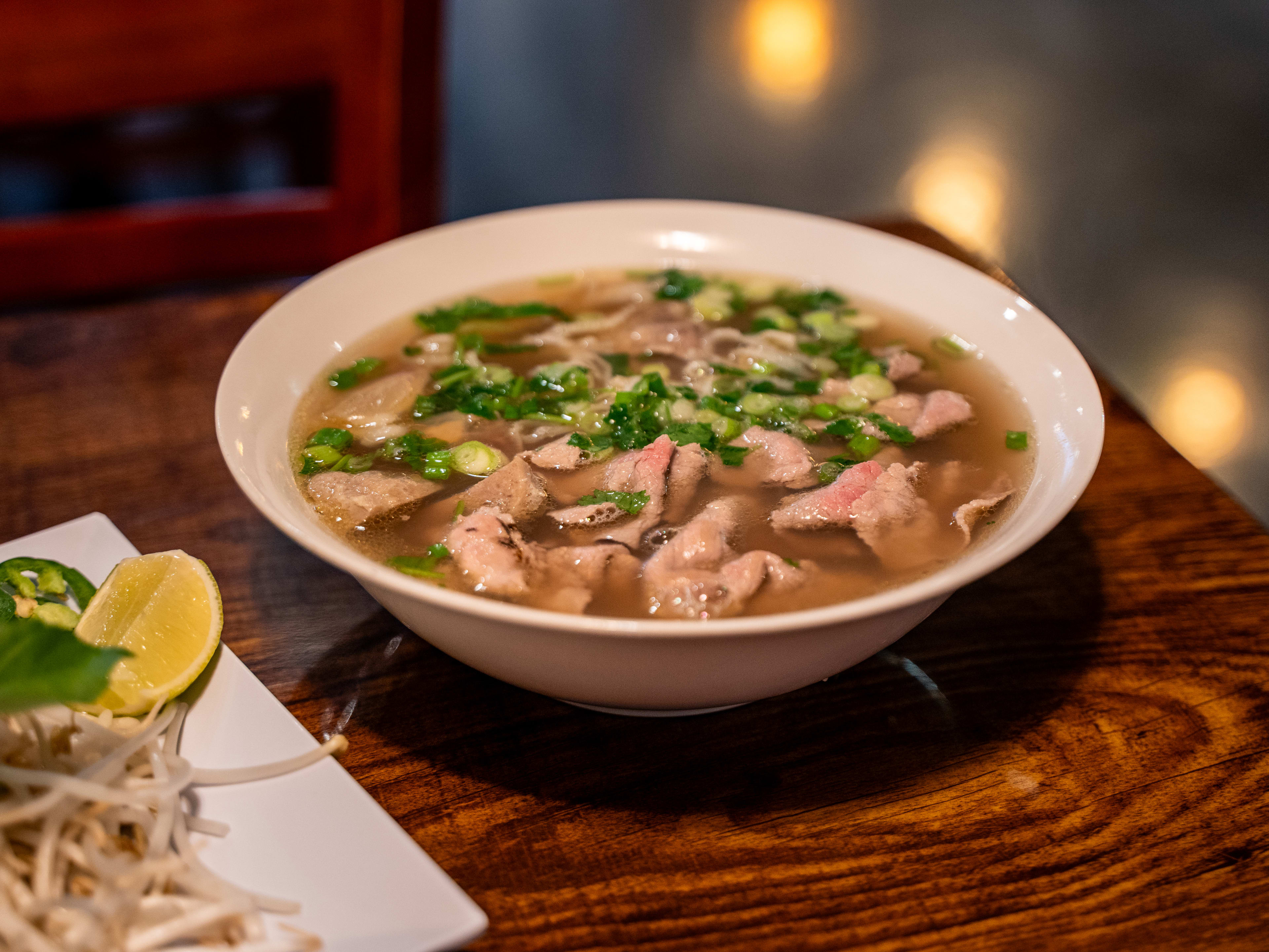 Bowl of beef pho in a huge bowl on wooden table