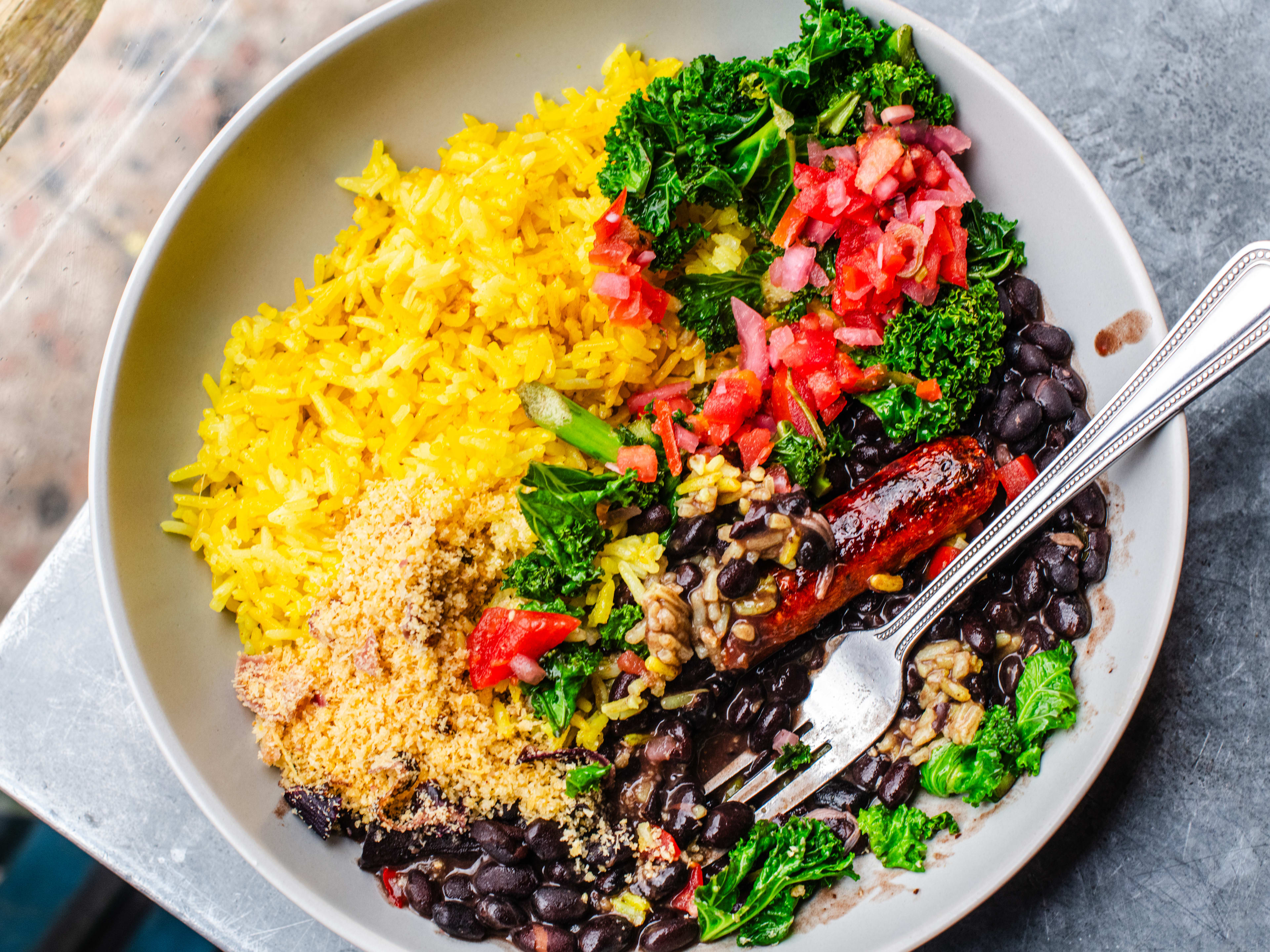 Bowl of feijoada (bean stew) and vegan sausage, with a fork in the bowl.