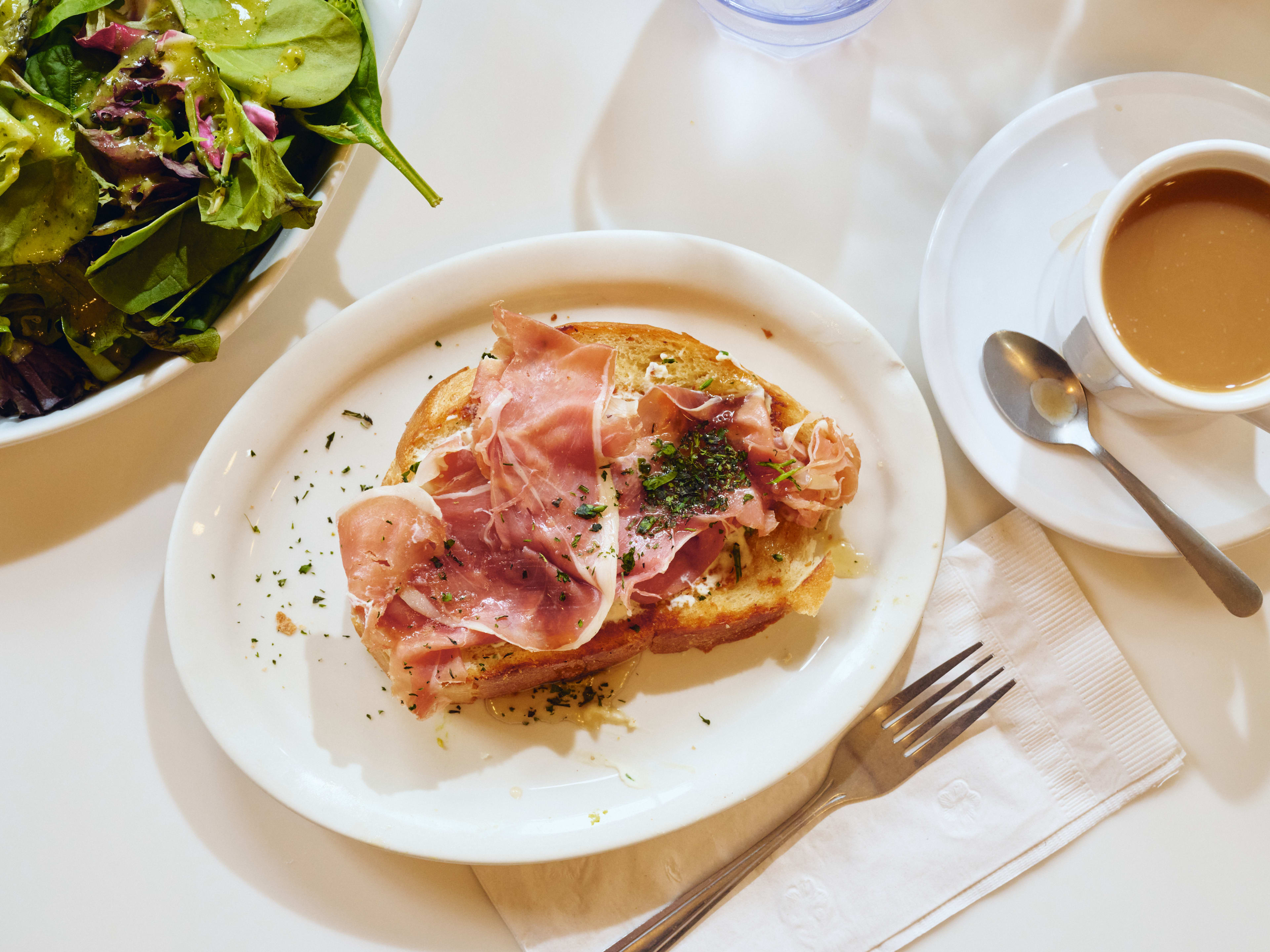 Prosciutto toast served with fresh greens and a hot coffee at Toast