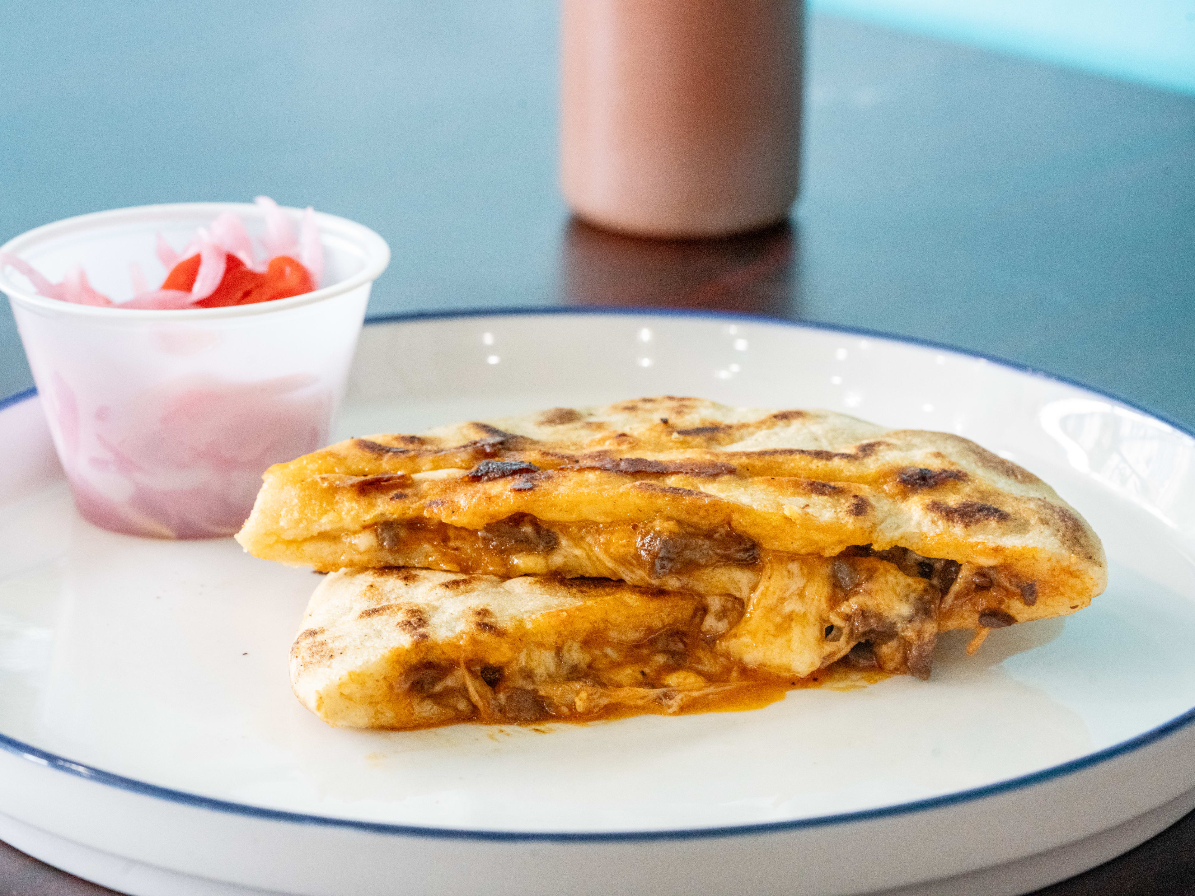 A pupusa cut in half on a plate.