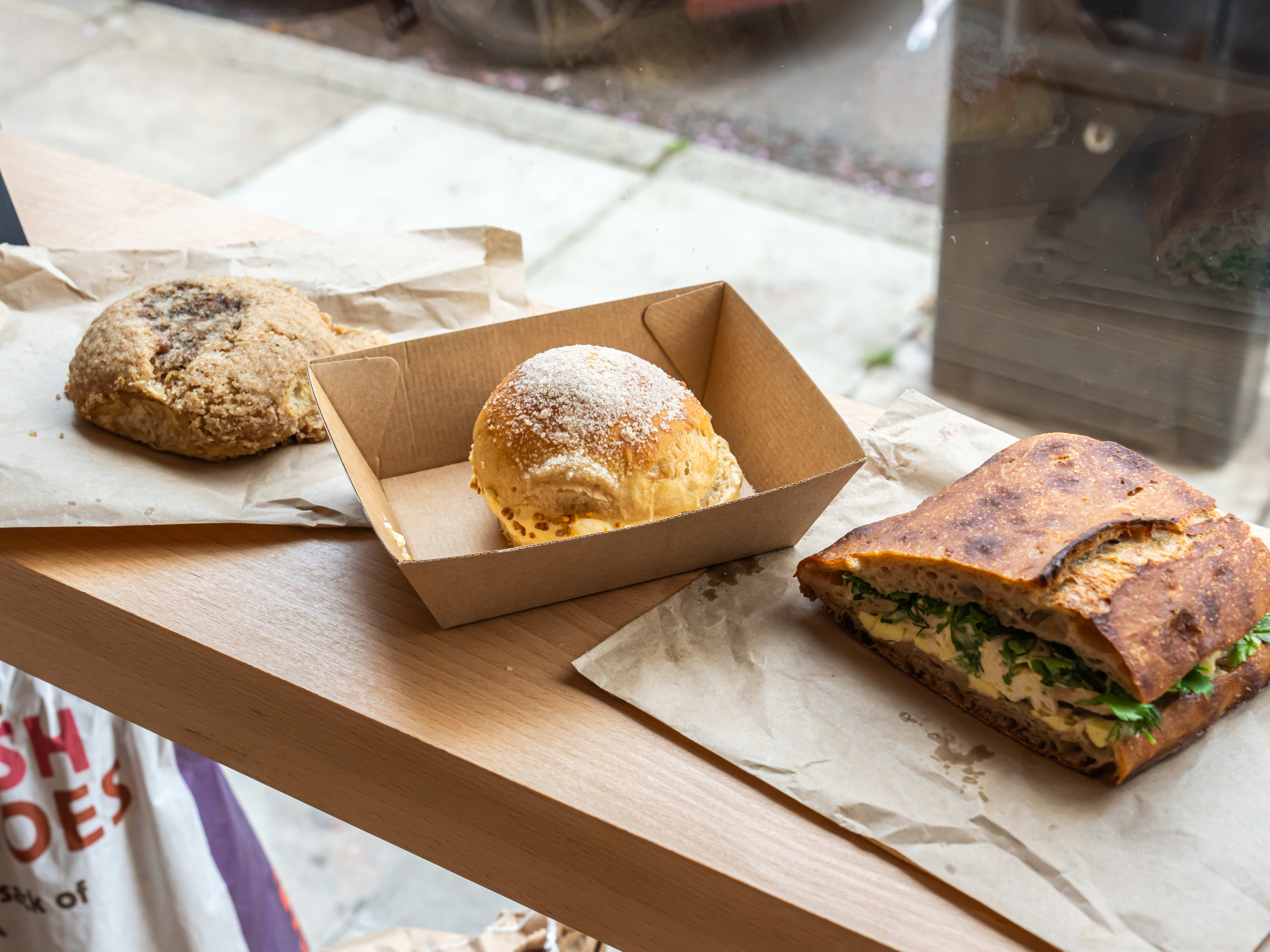 Two buns and a sandwich on the window counter at Quince Bakery