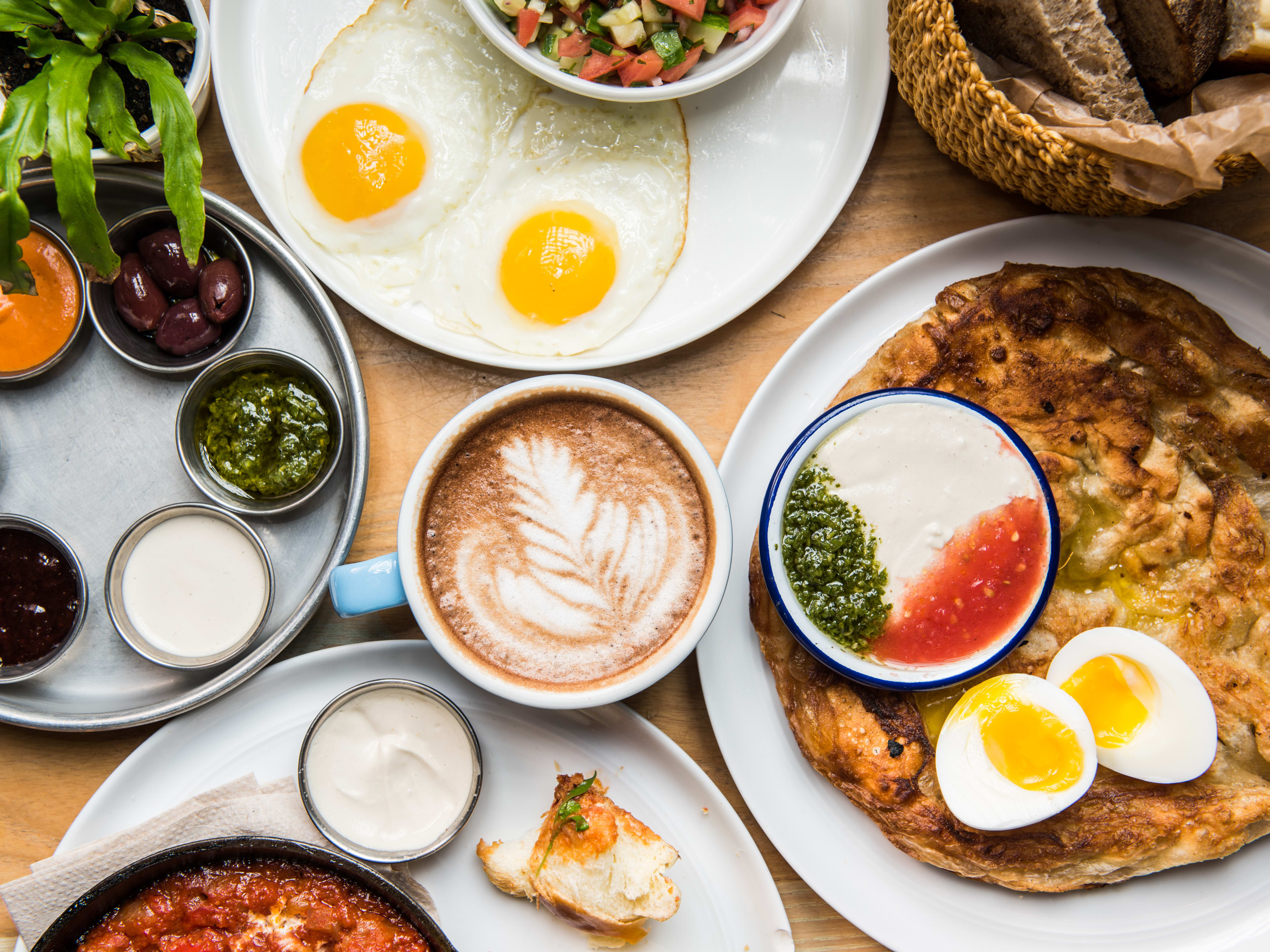 A spread of brunch food on a table with a latte in the middle.