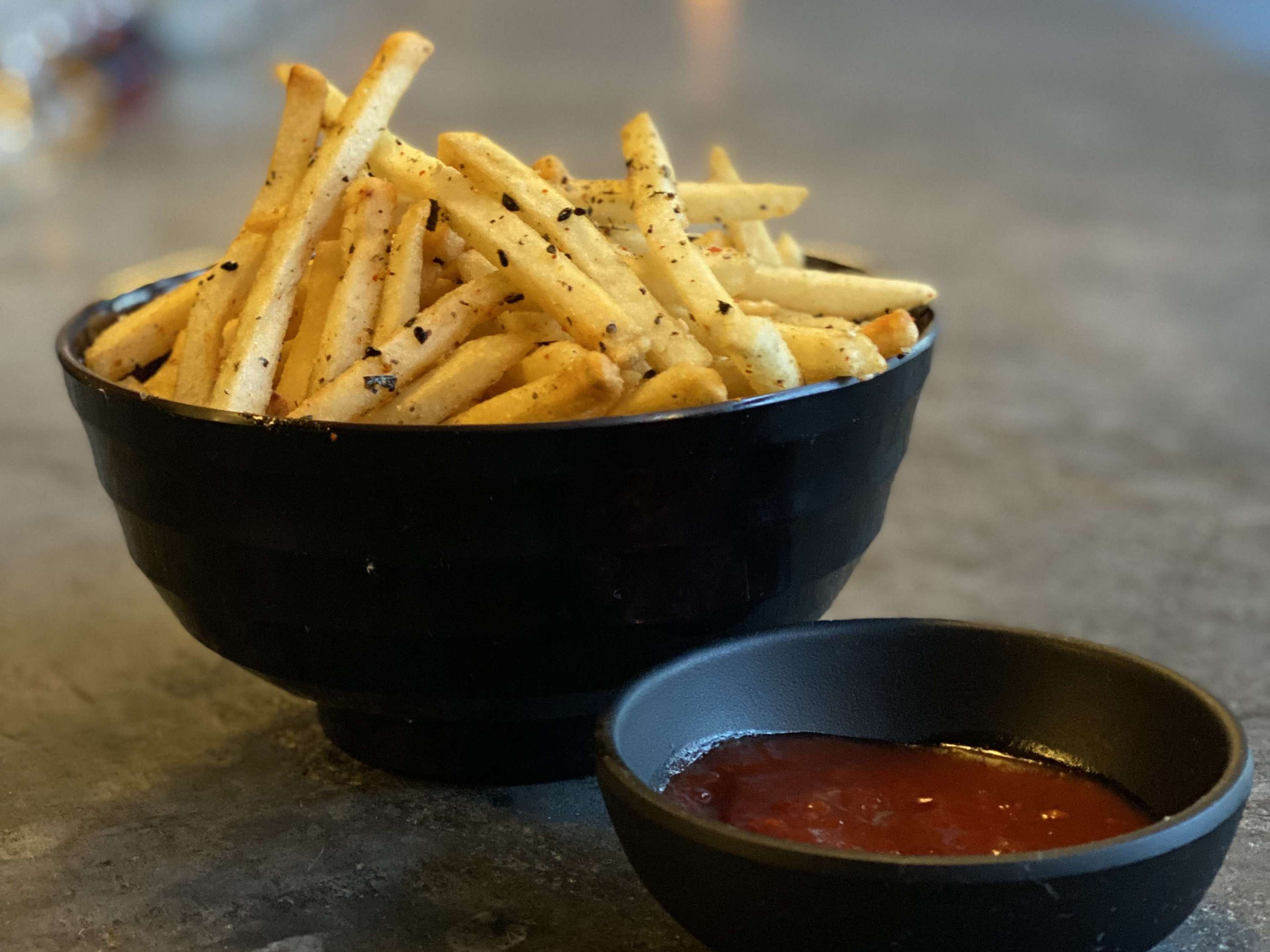 A cup of fries served with a side of gochujang ketchup.