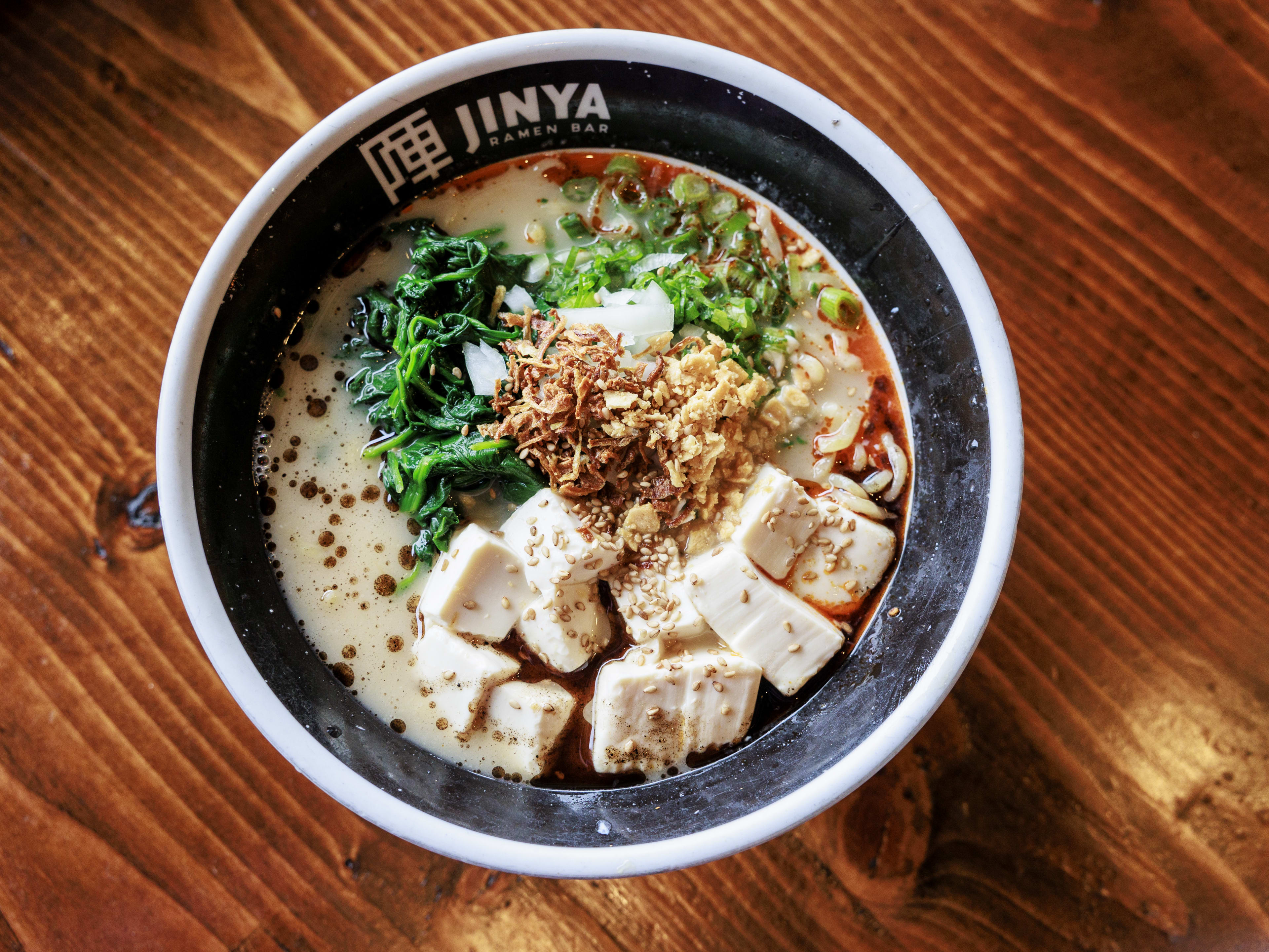 bowl of vegan ramen topped with tofu, chili oil, scallions, and greens.