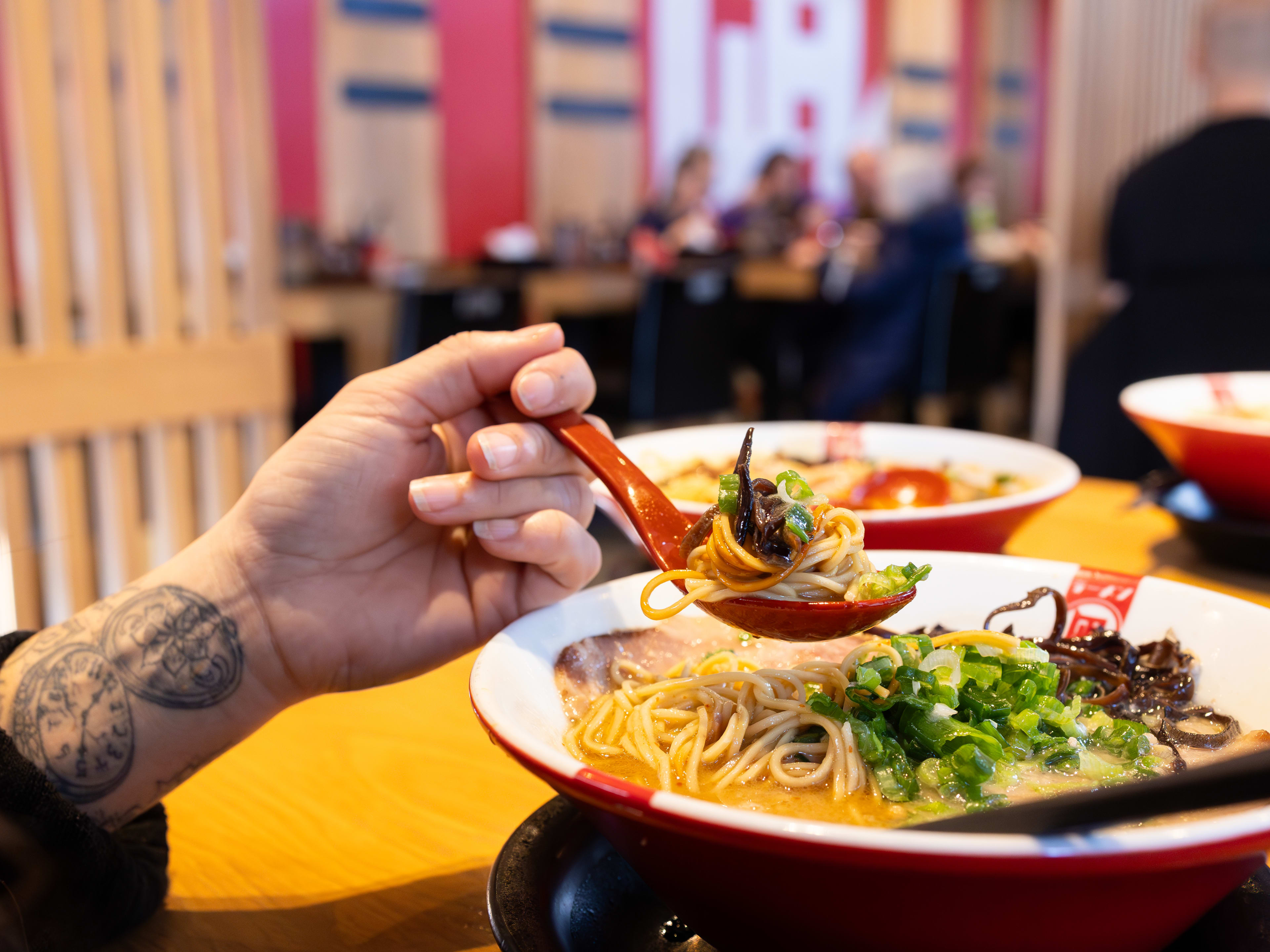 A person holding a spoonful of ramen.