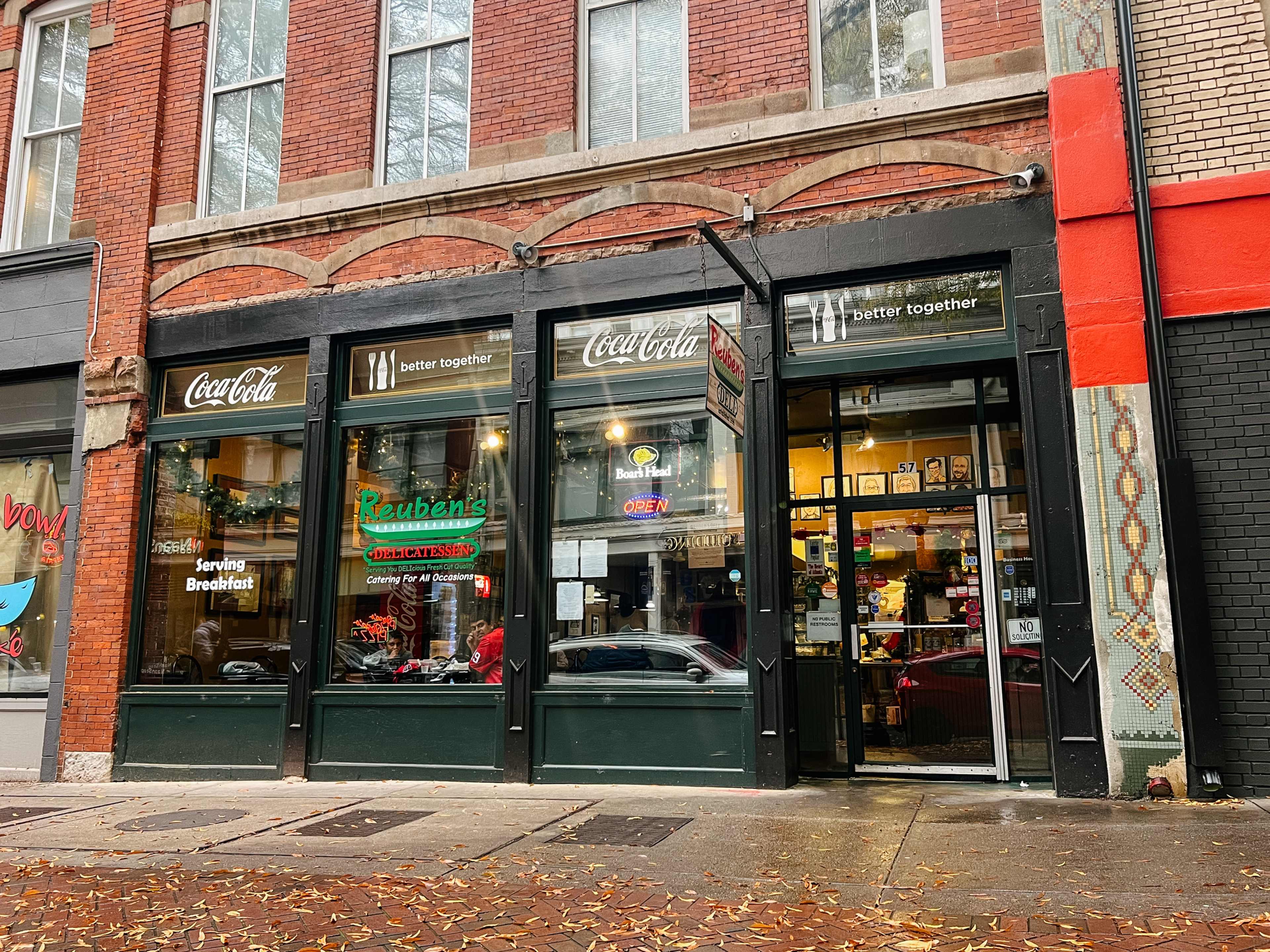 The exterior of Reuben's Deli beneath a brick building.