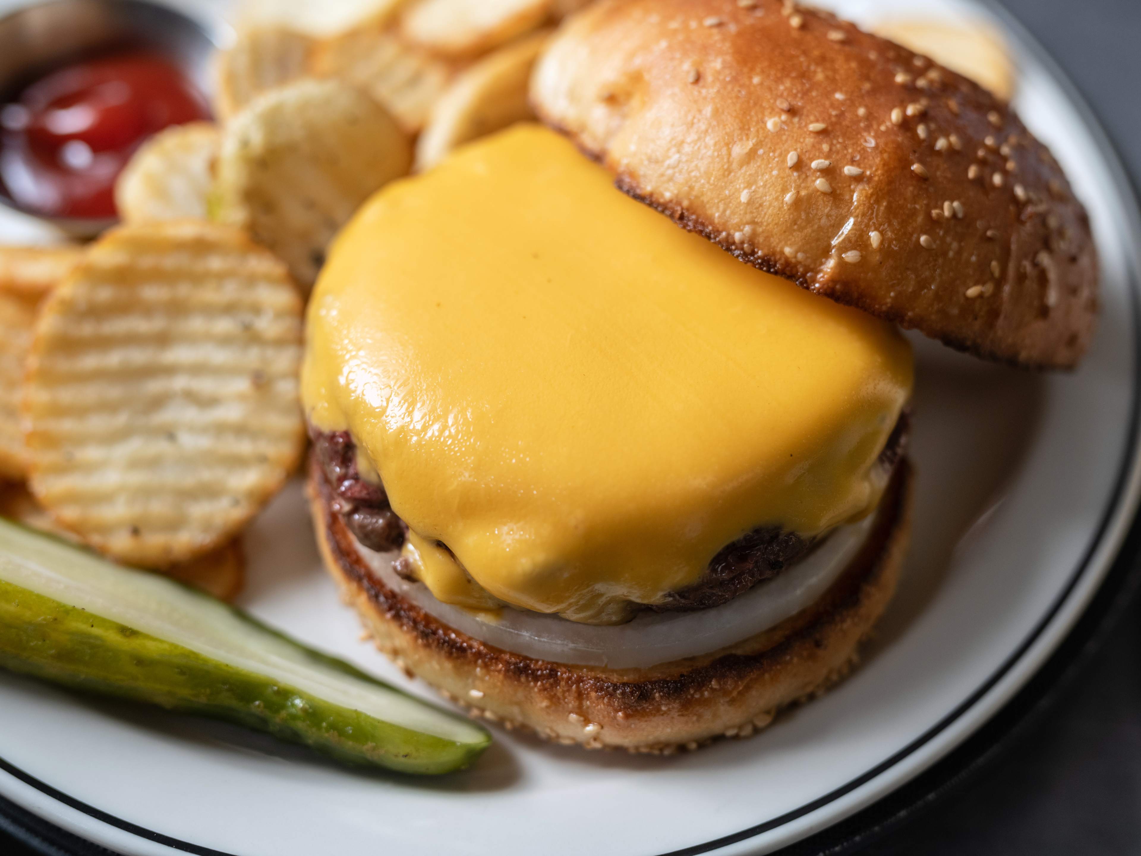 a burger with cottage fries and a pickle spear