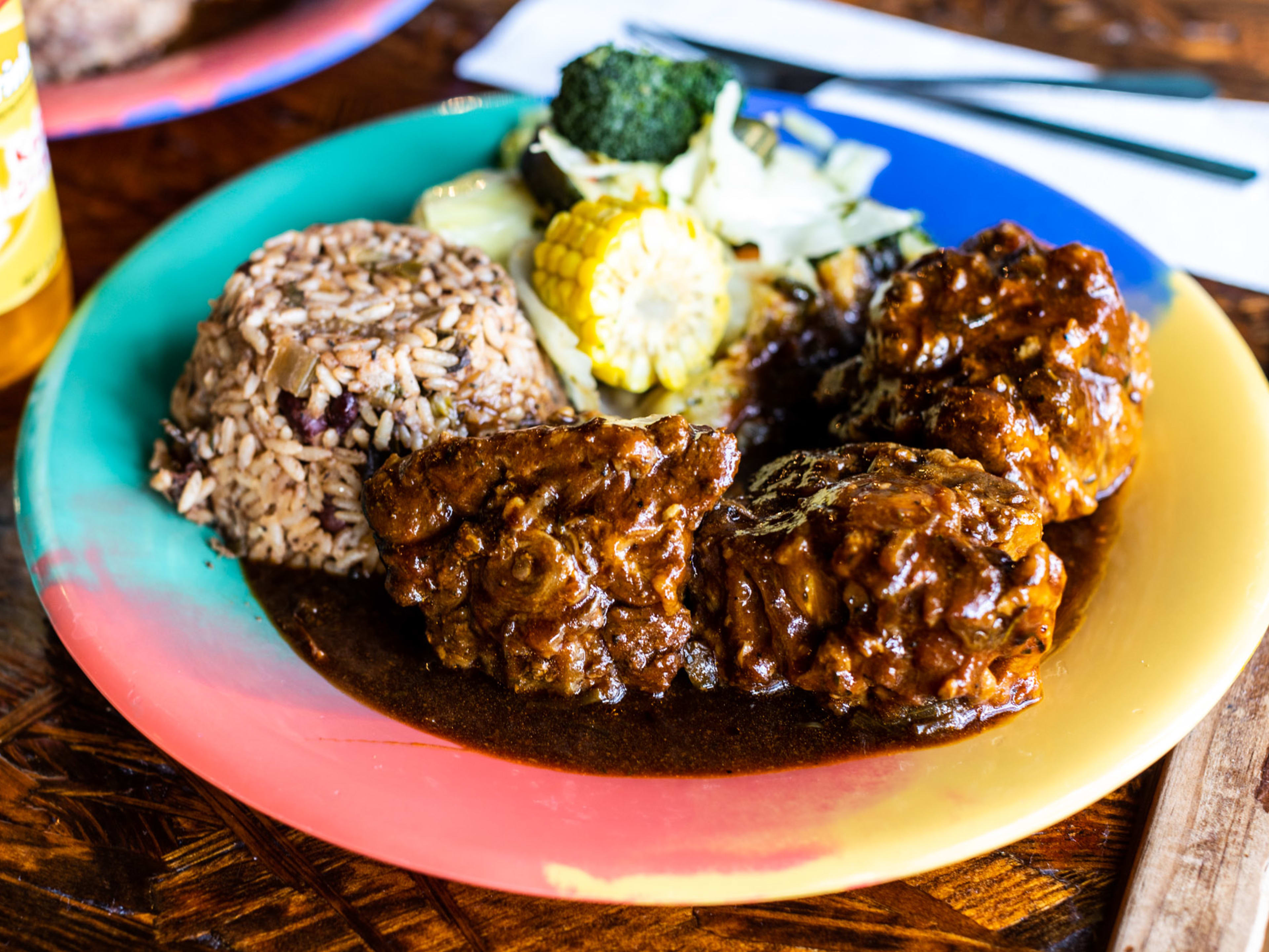 The braised oxtail with sides on a colorful plate from Reggae Hut.