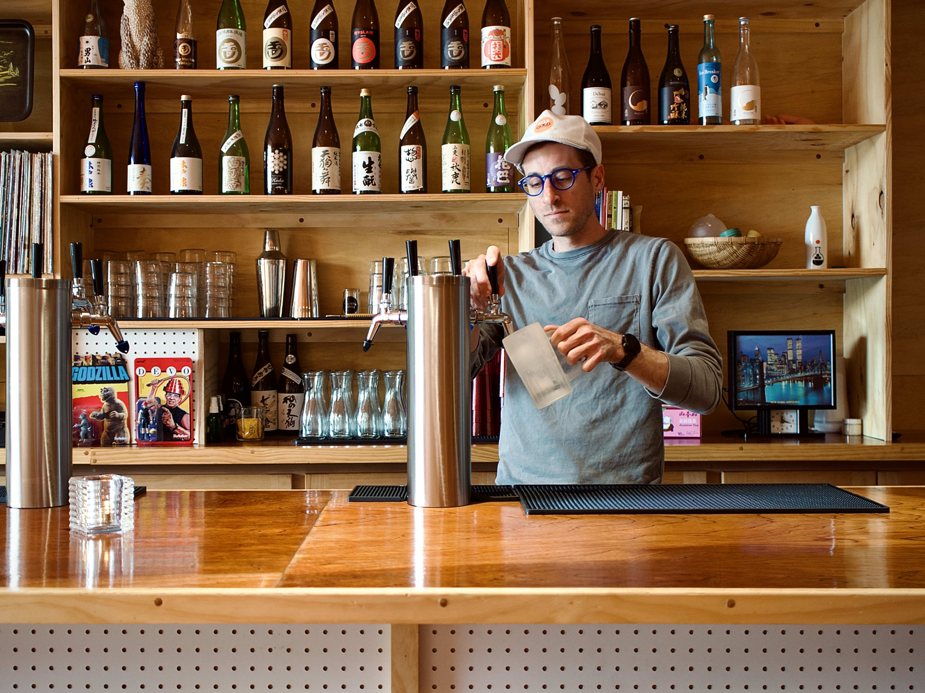 Bartender serving a drink from a tap at a wood bar and counter.