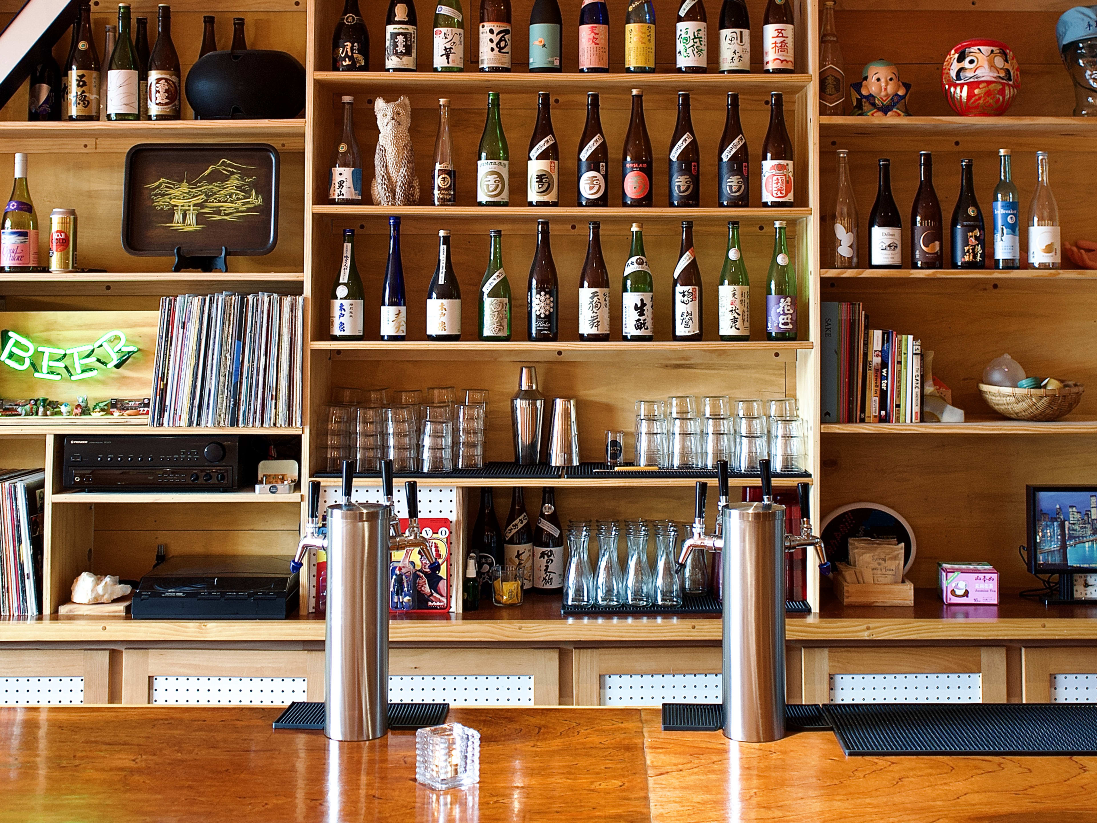 Light wooden bar space with shelves full of craft sake at Rice Vice