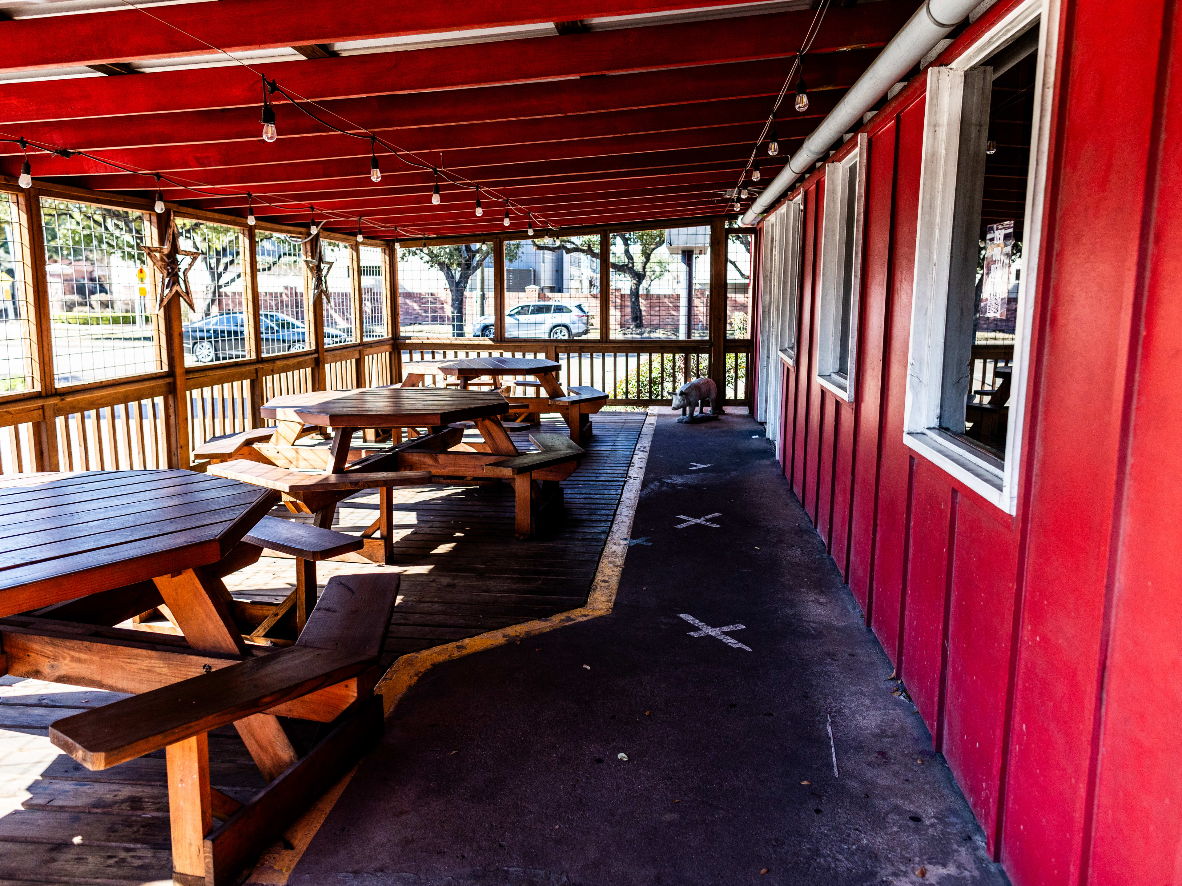 restaurant patio with wood patio tables and red walls and patrio roof