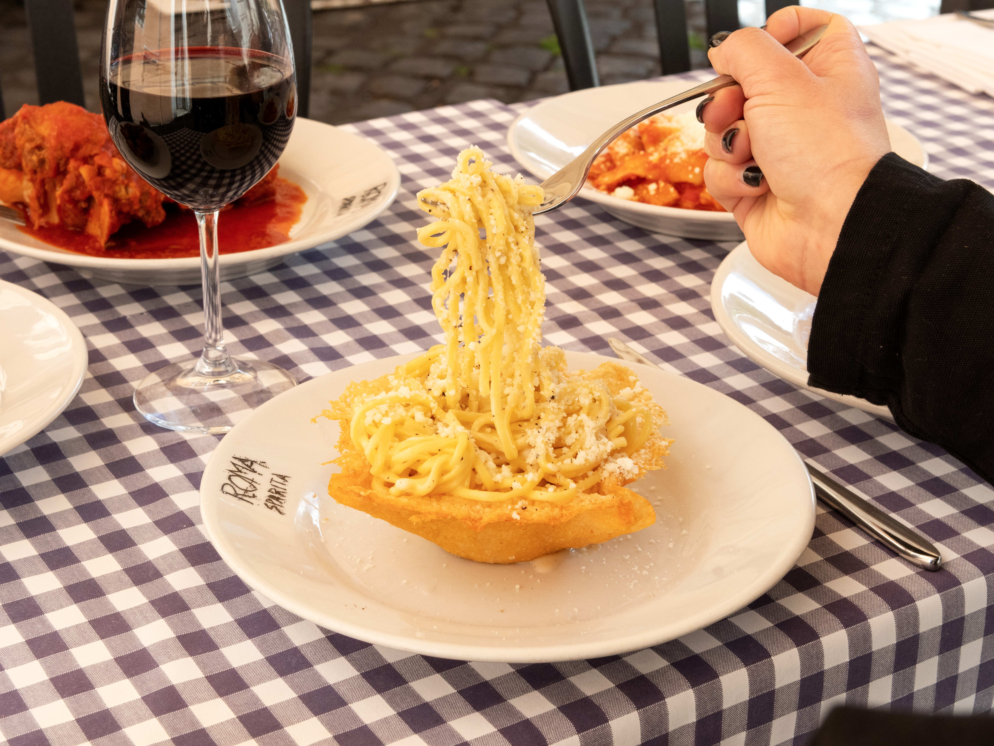 Woman eating Cacio e Pepe out of baked parmesan shell at Roma Sparita