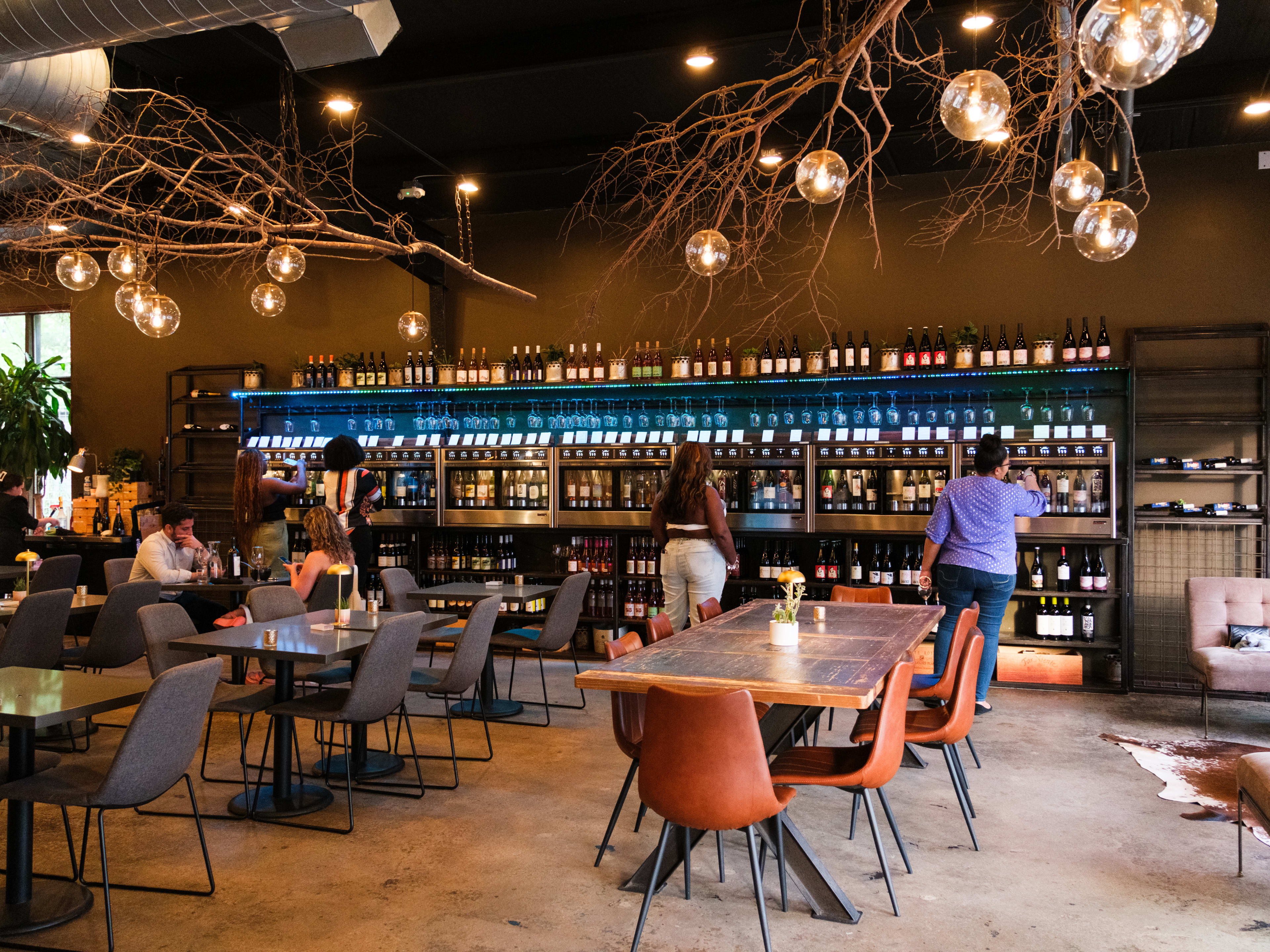 People sit at tables and pour wine from self-serve stations at Roots Wine Bar.