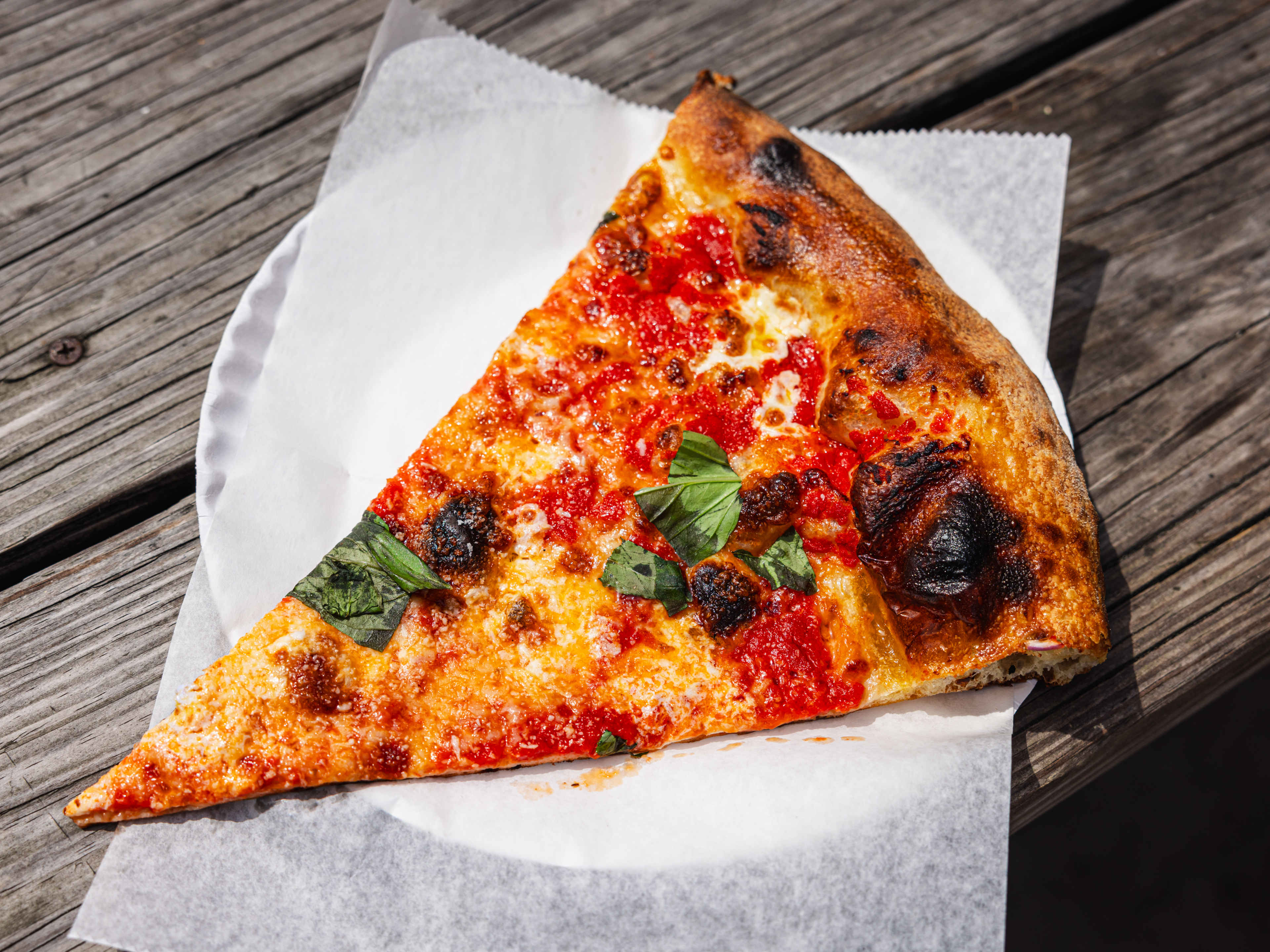 A slice of cheese pizza on a white paper plate.