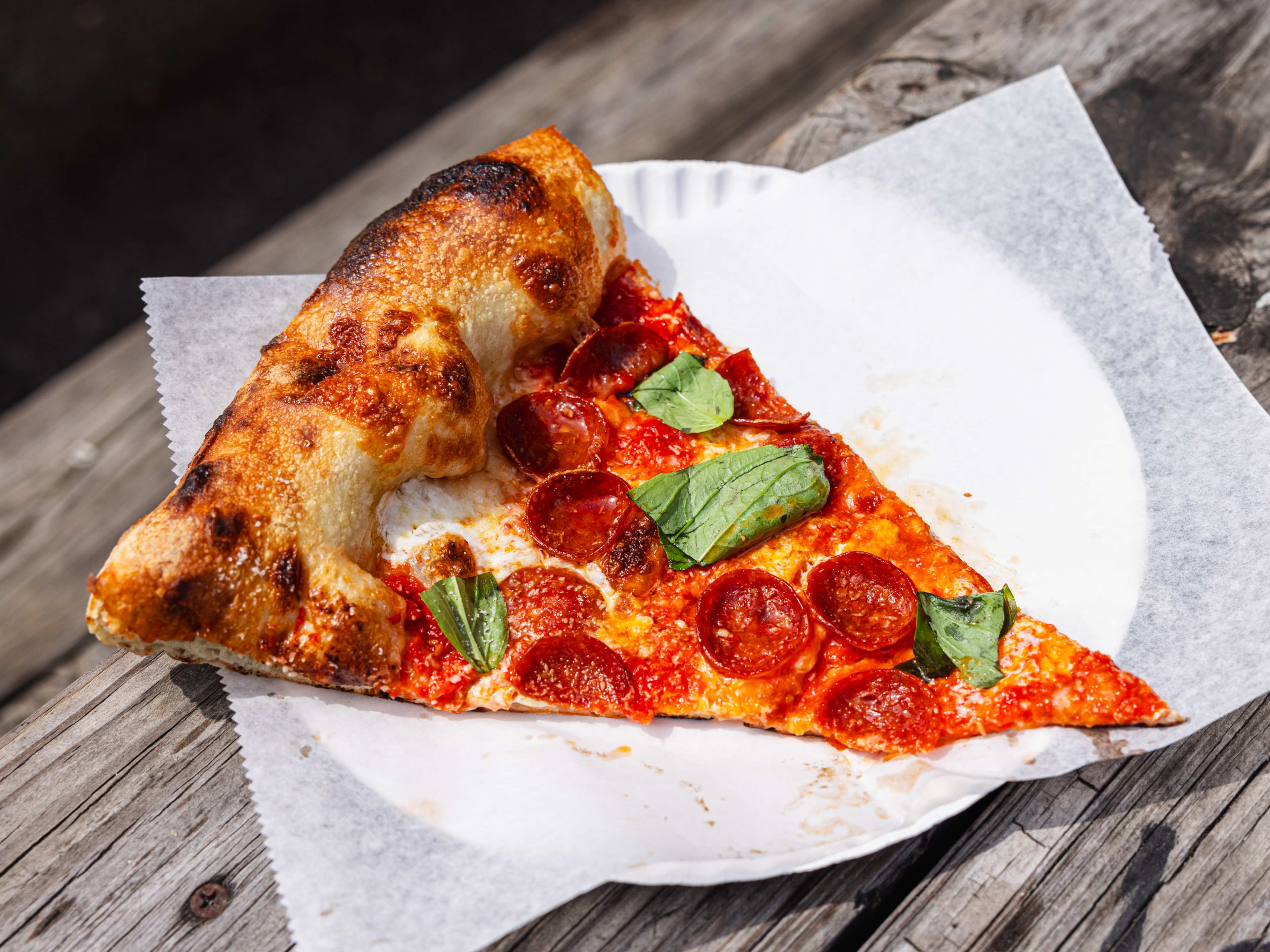 A piece of pepperoni pizza on a paper plate.