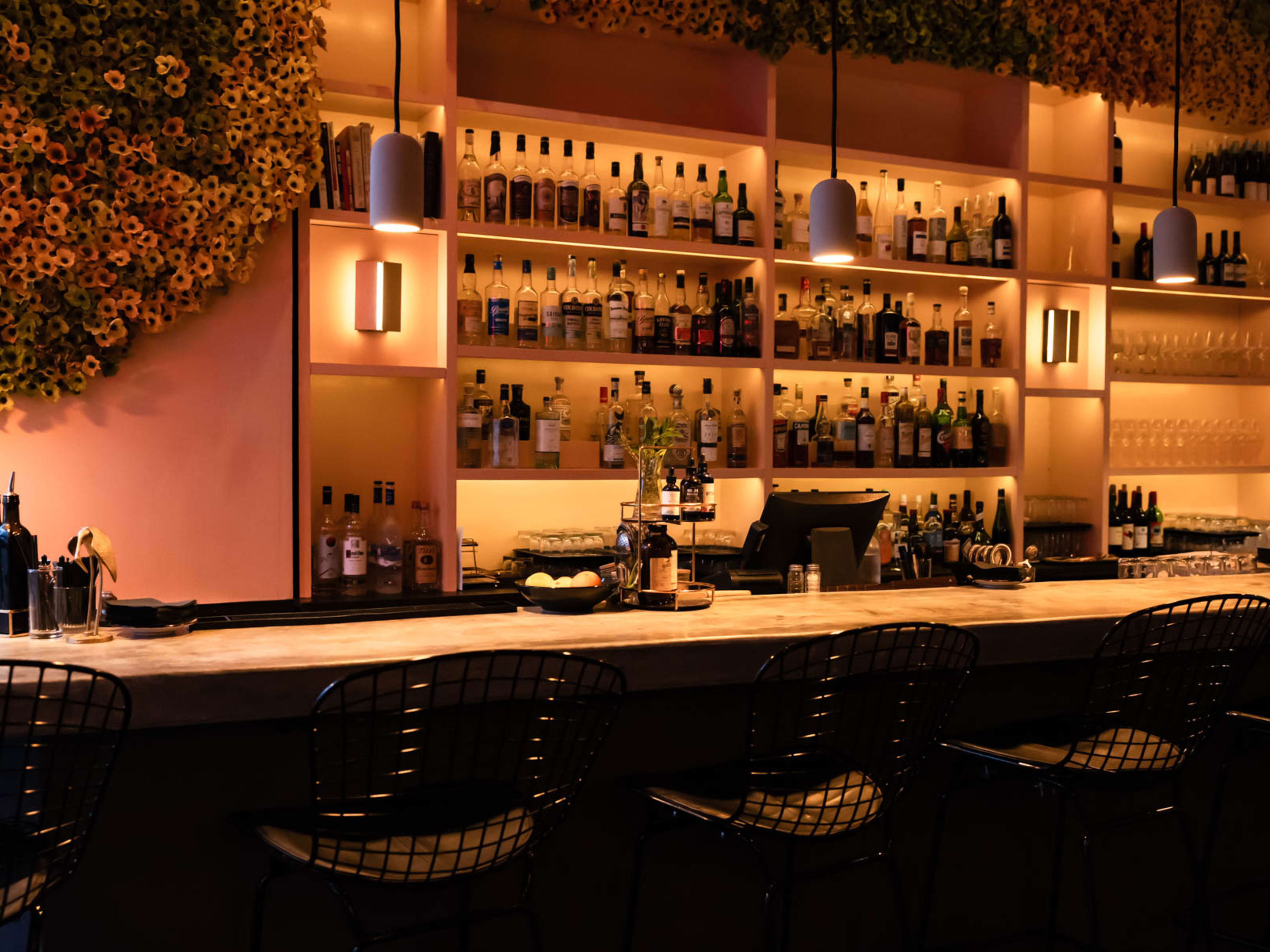 A warmly lit bar with a large floral arrangement framing the top.