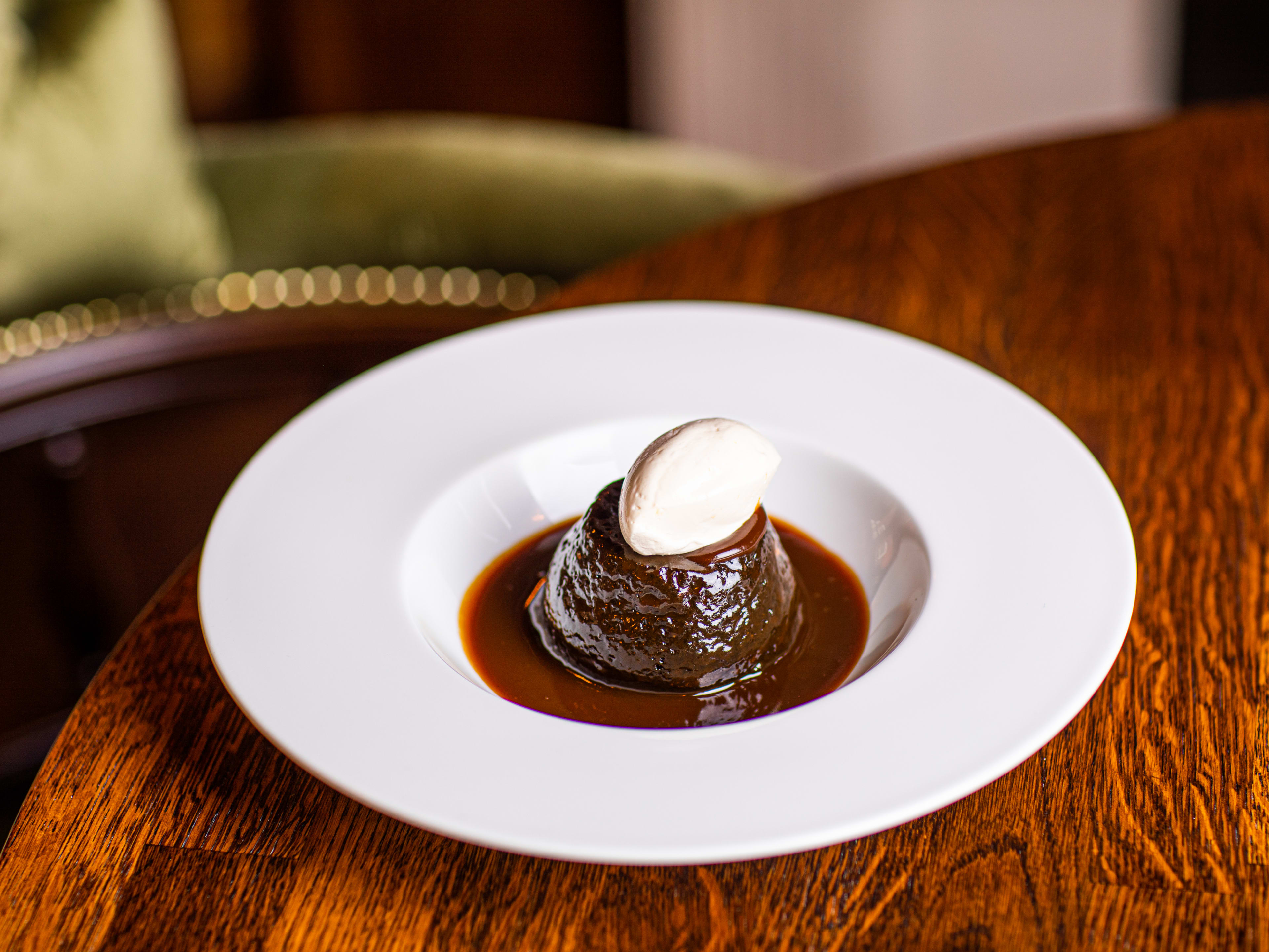 A sticky toffee pudding with a quenelle of cream on top.