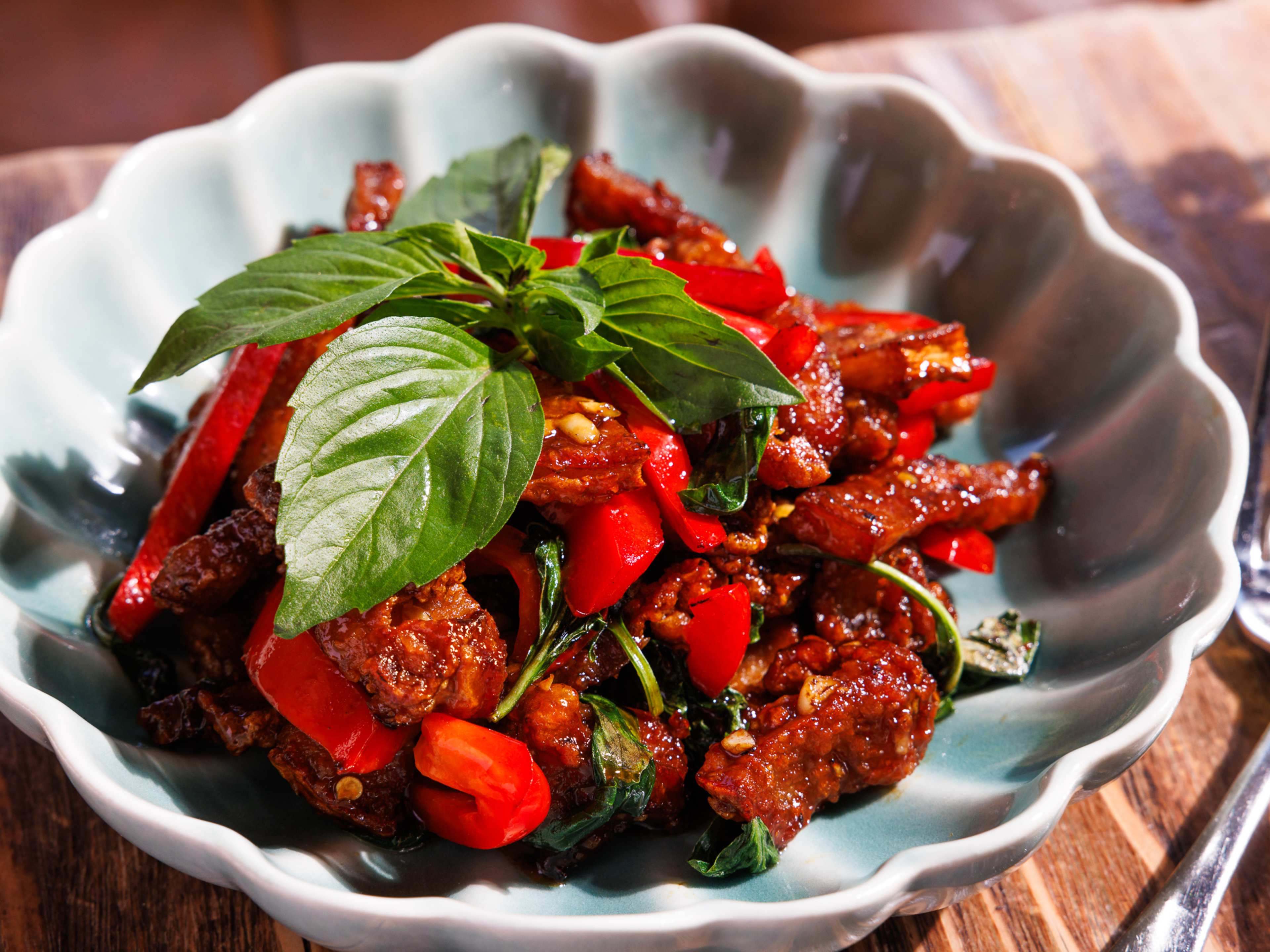 a bowl of fried pork belly with chilis and basil