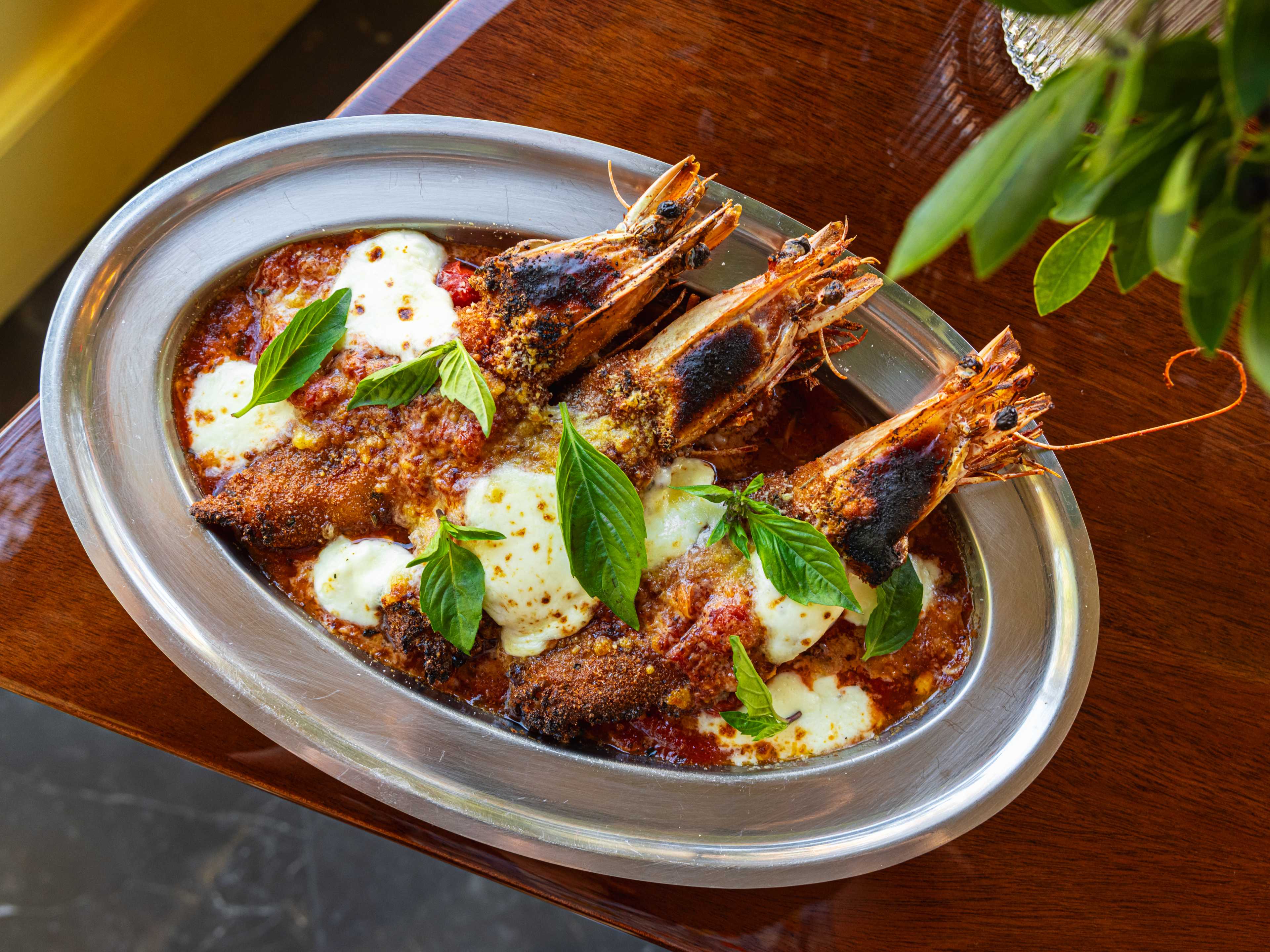 three shrimp parm,  on a sizzle tray with melted cheese and basil