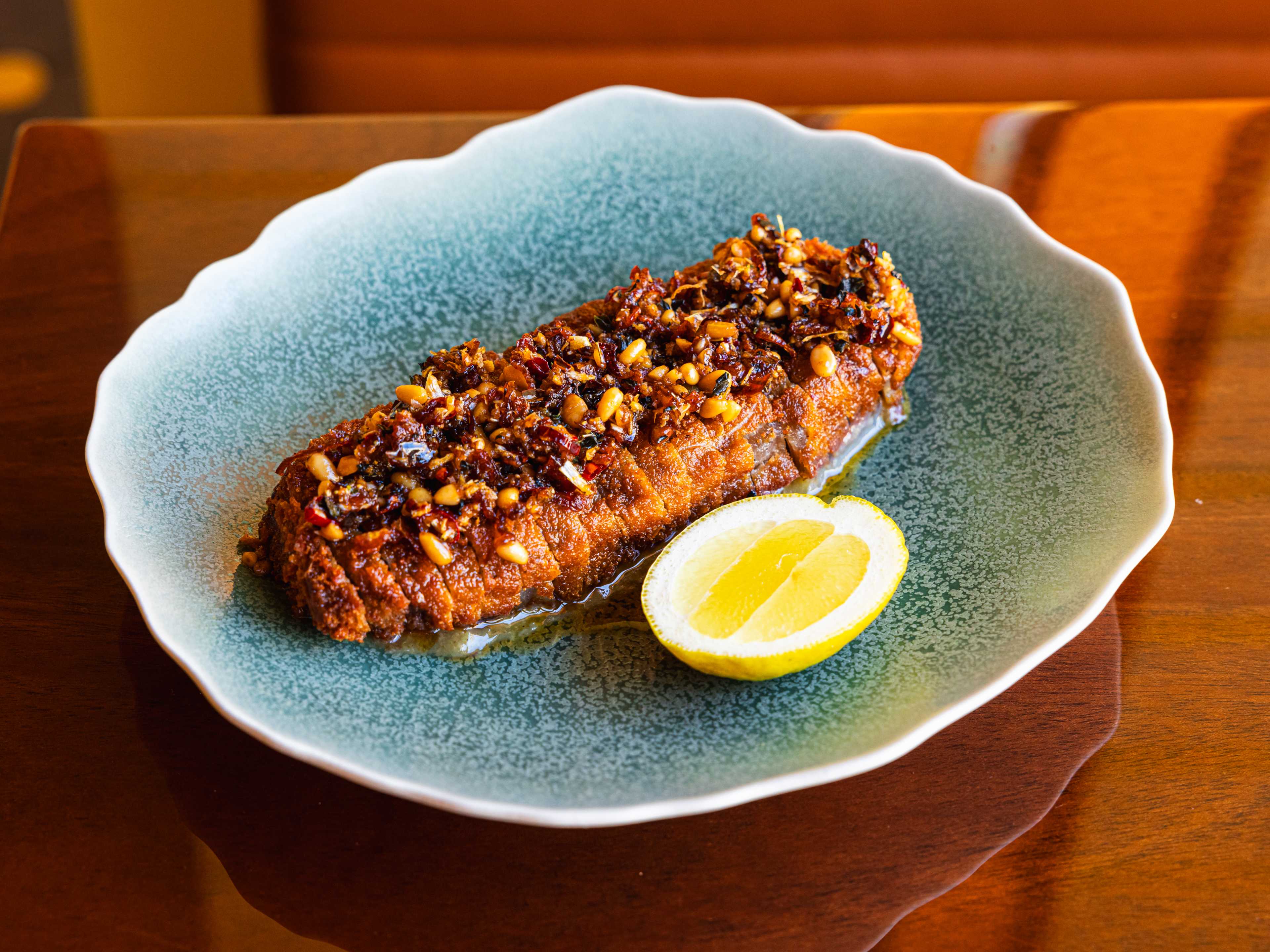 a katsu steak with chile crisp and a lemon wedge