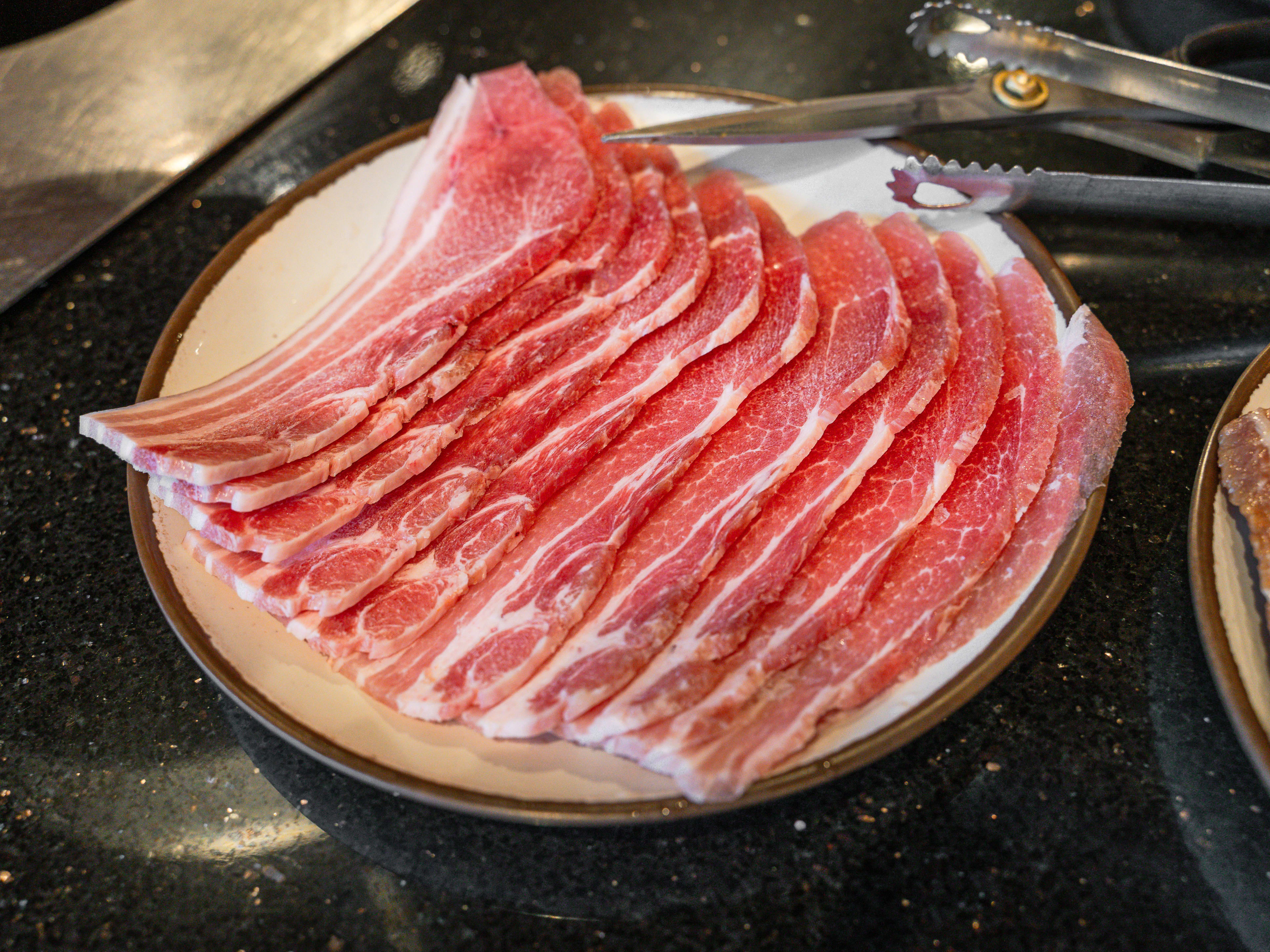 Slices of raw pork belly on a plate.