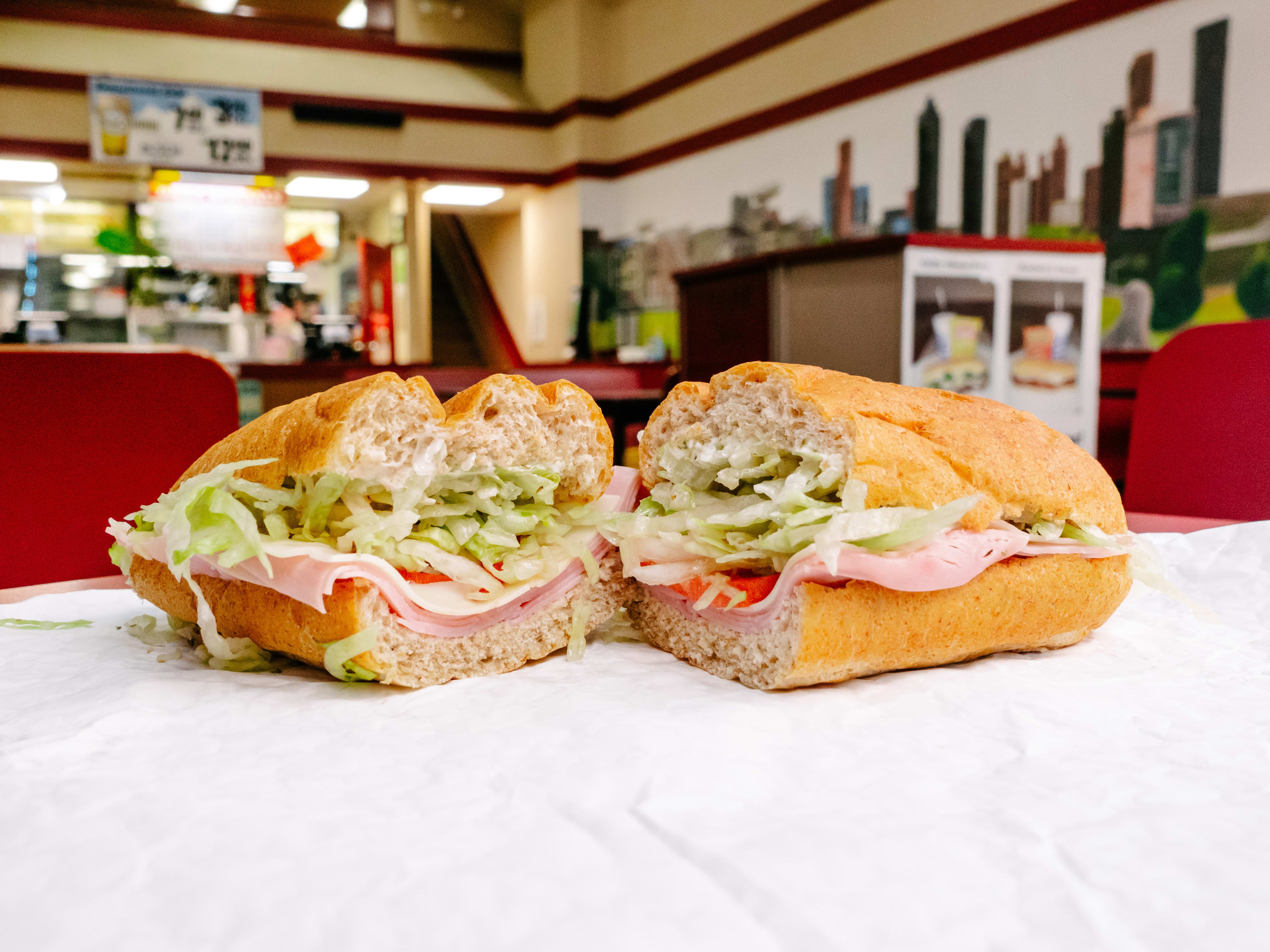 A ham and turket sub with tomatoes and lettuce.