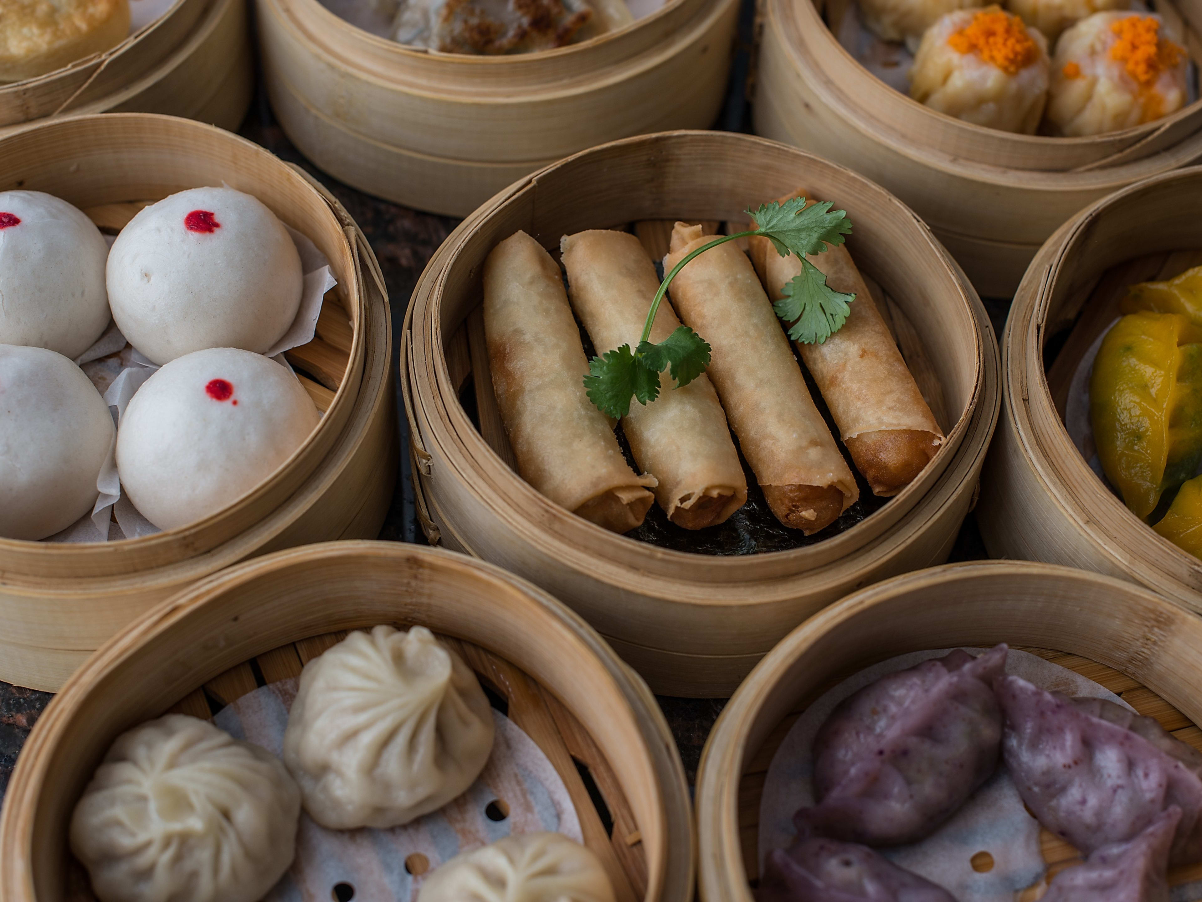 Spring rolls, and different types of dumplings and shumai in various steamer baskets