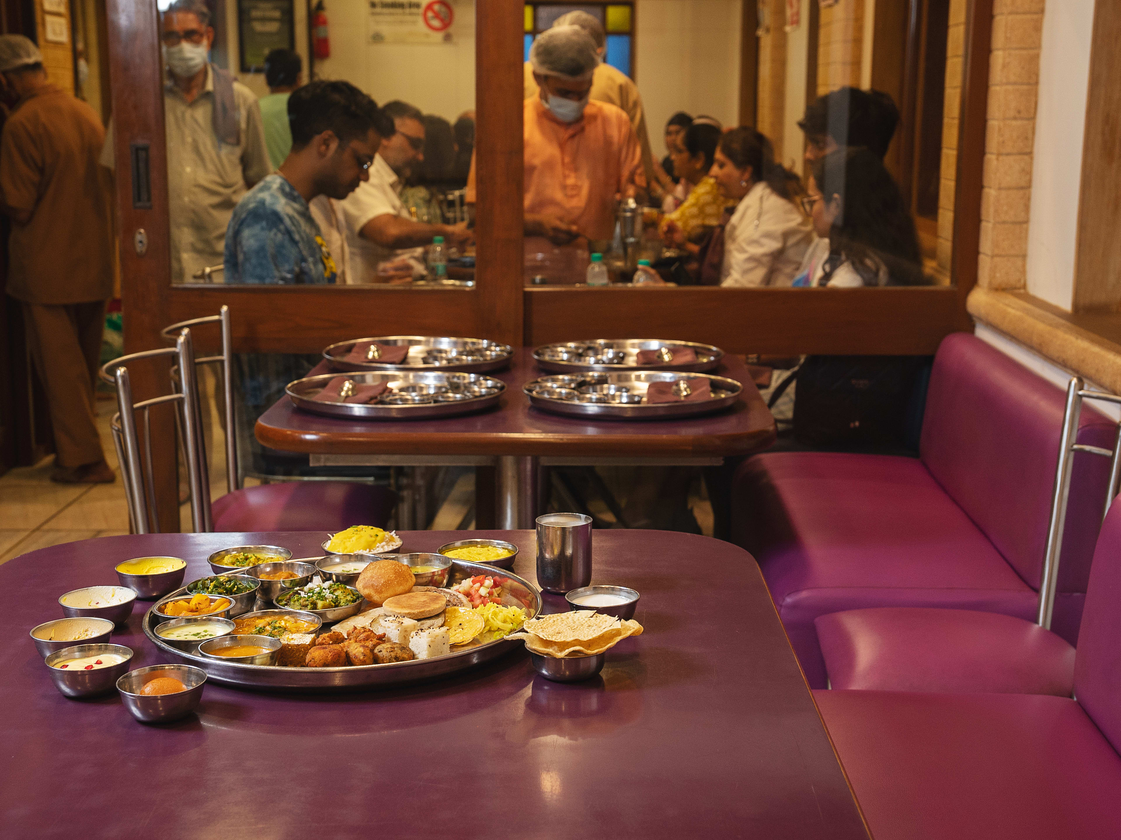 Thali on tin tray amidst busy lunch service at Shree Thaker Bhojanalay