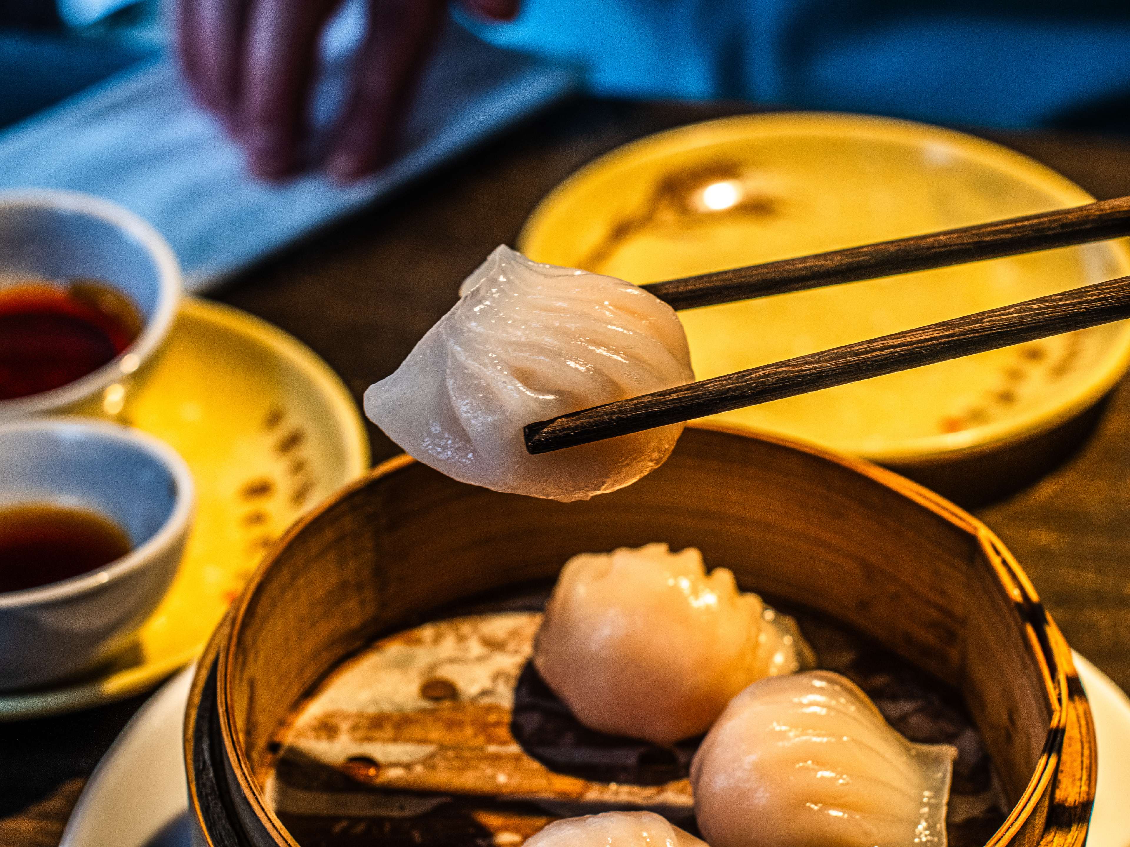 A prawn and scallop dumpling held up by chopsticks from Sichuan Popo.