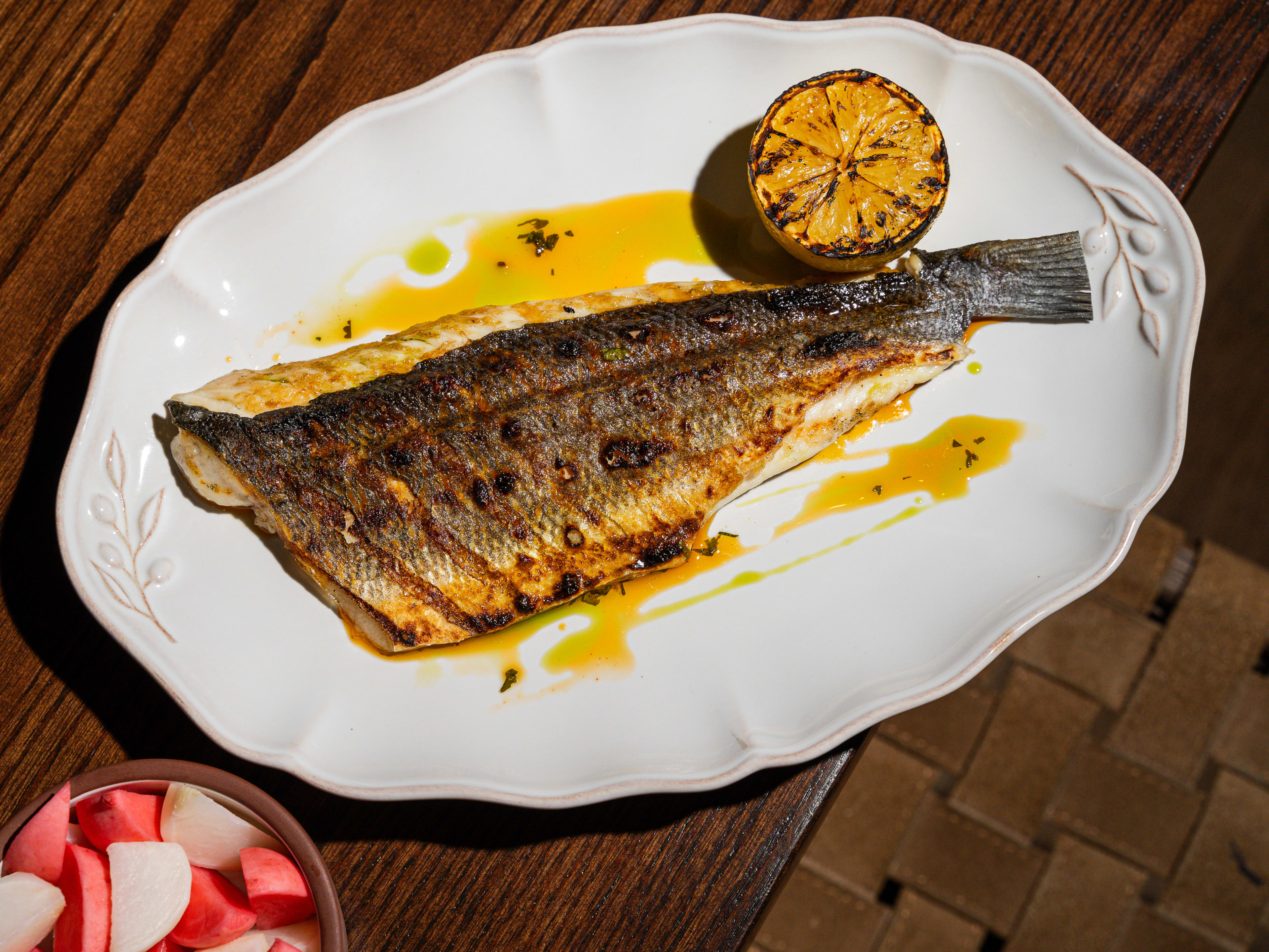 Plate with a whole grilled sea bass with half a grilled lemon