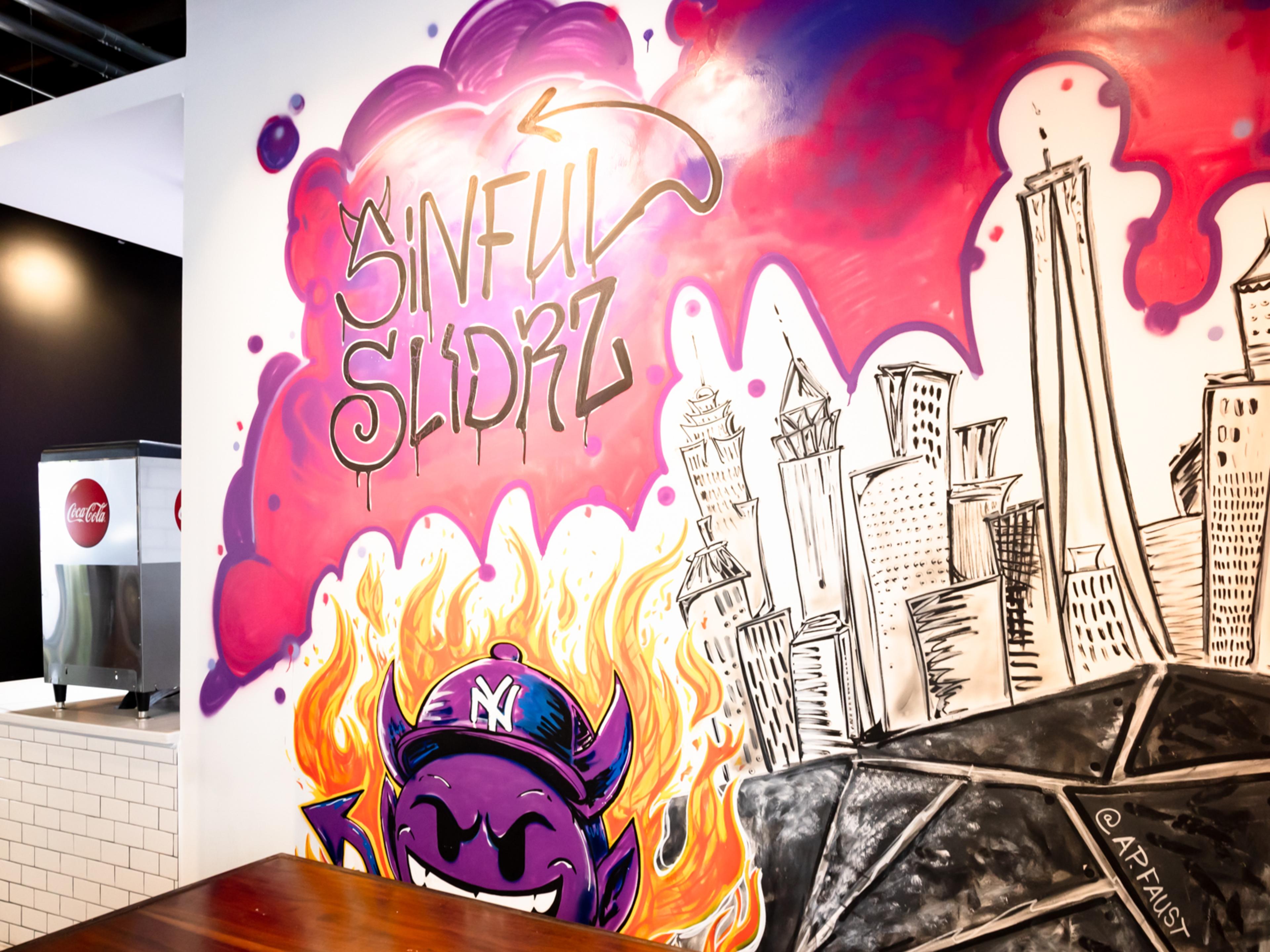 Sinful Slidrz mural with a skyline and devil emoji.