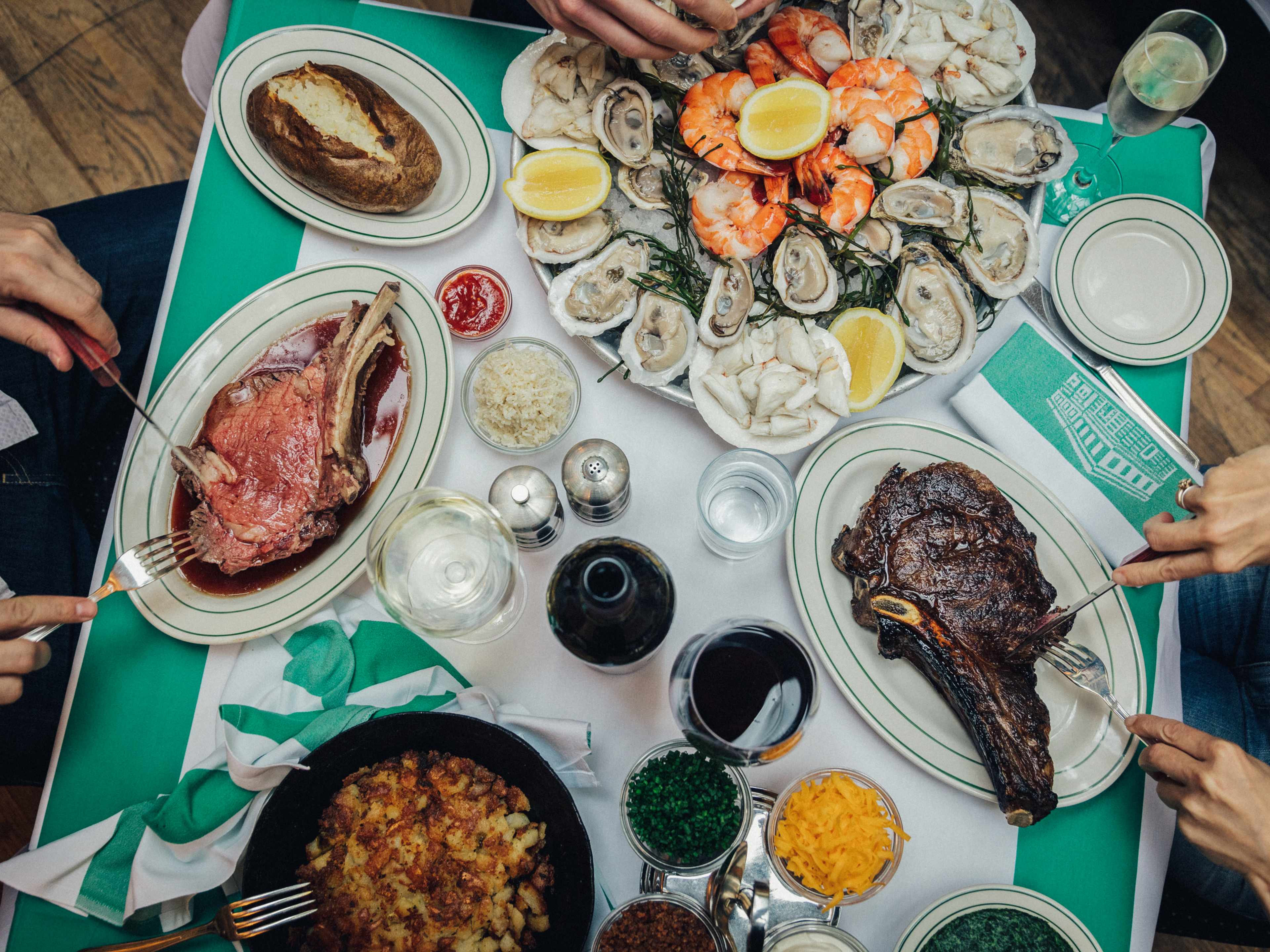 A table covered in oysters, steak, shrimp cocktail, prime rib, and more.