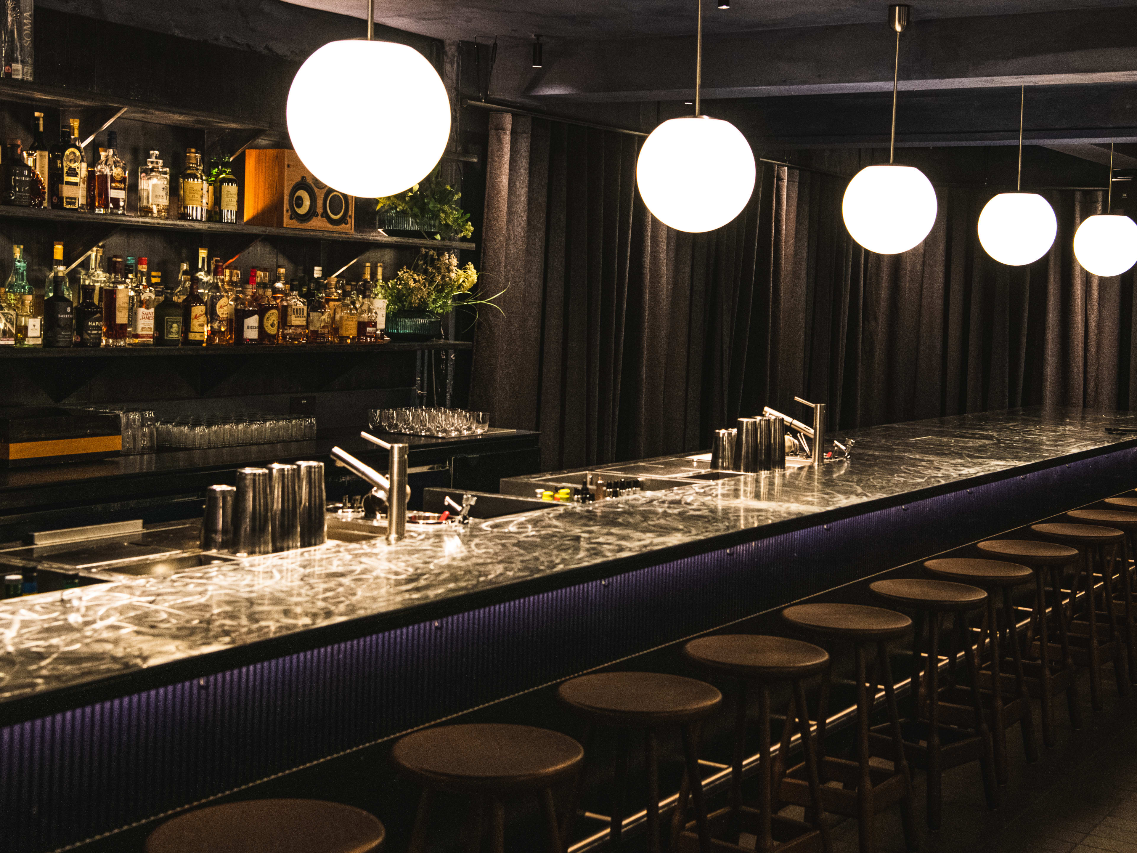 The black and grey interior of Soma with orb pendant lights.