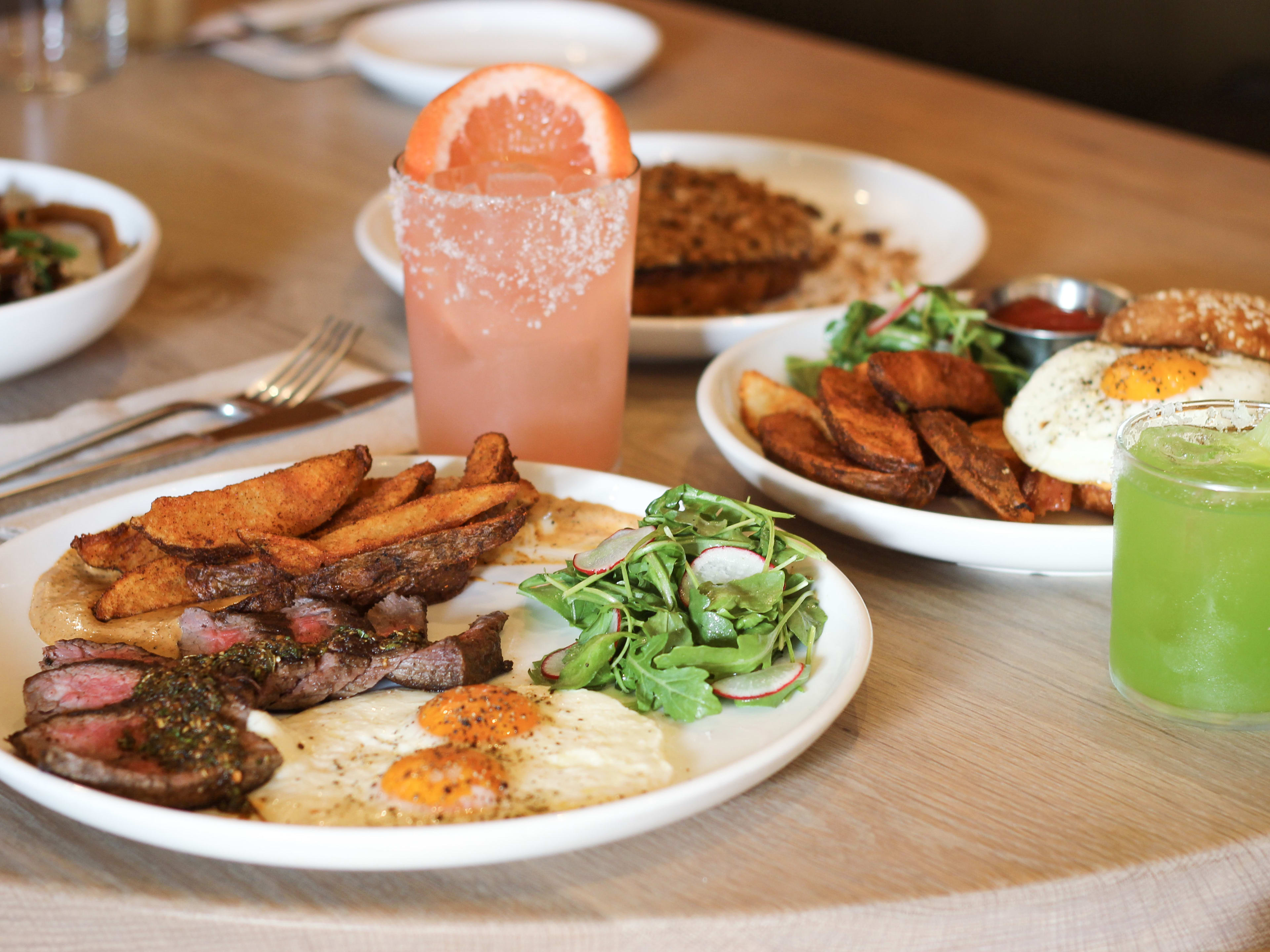 The steak and eggs surrounded by breakfast drinks and dishes from Paperboy.