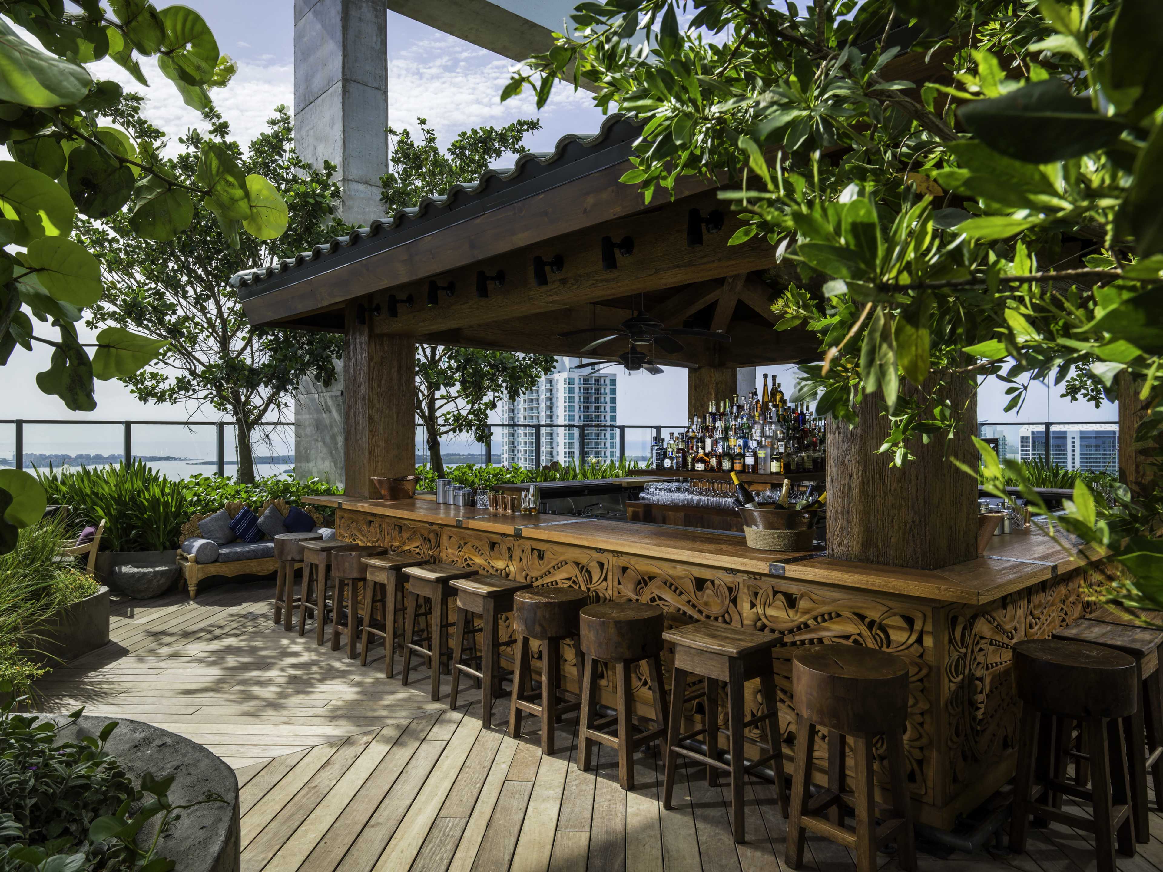 rooftop bar filled with trees and plants and a wooden bar area