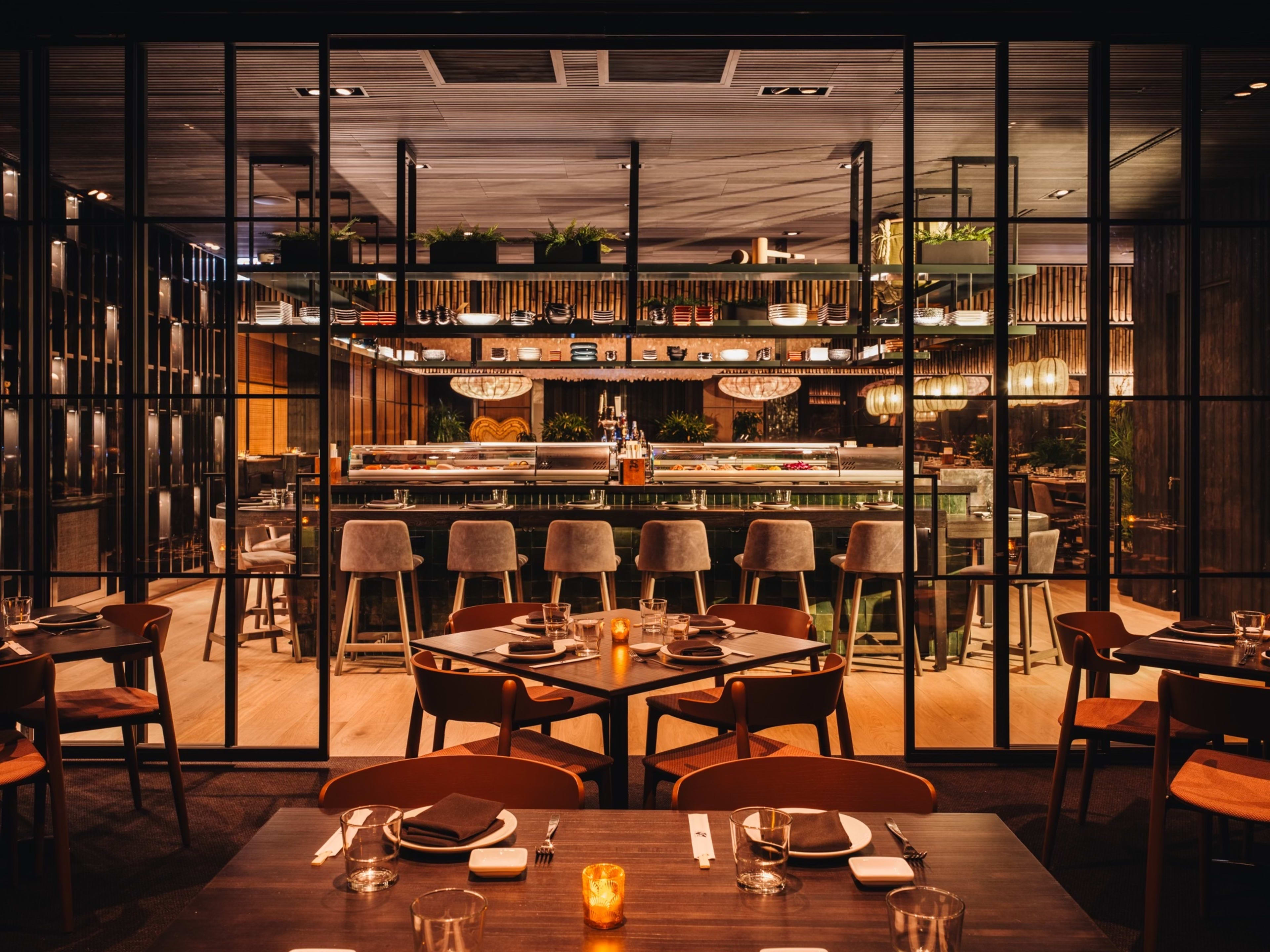 Interior dining room at Sunda with wooden tables, industrial metal decor, and low lighting