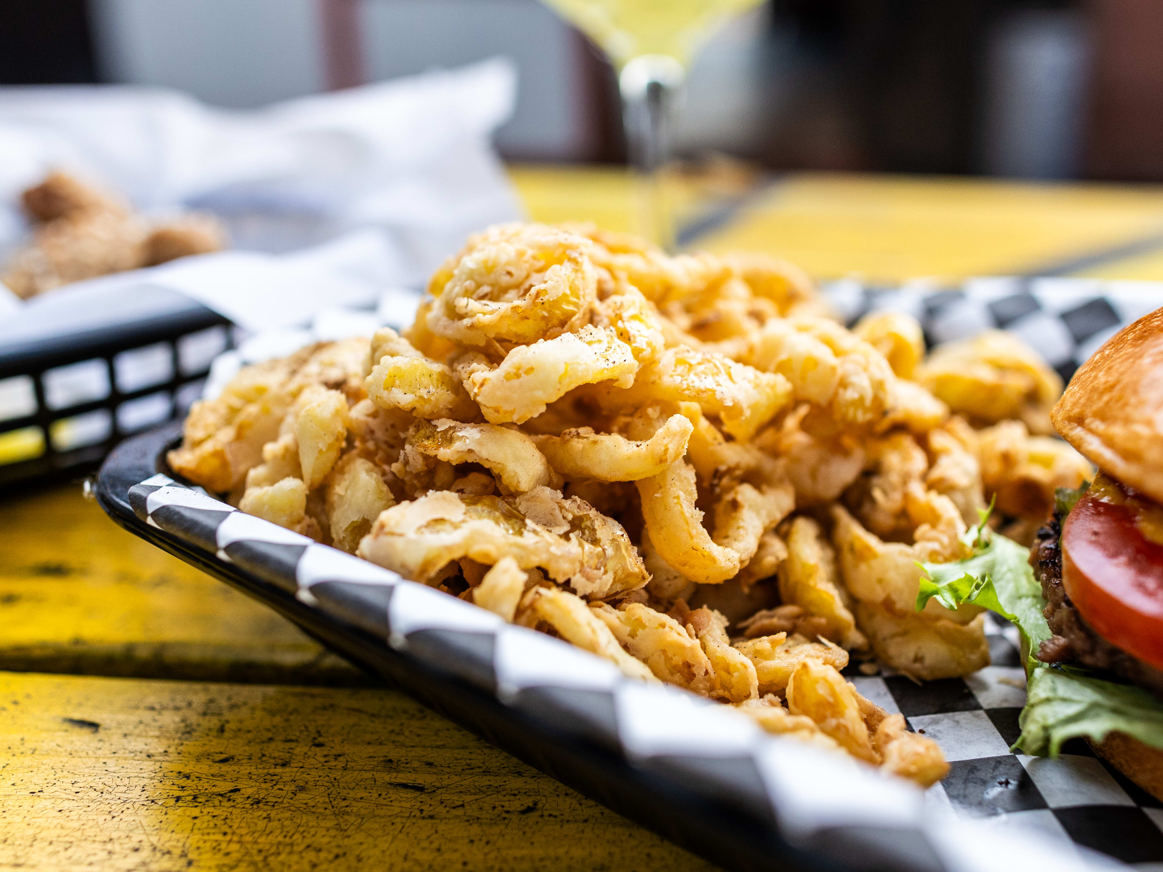 Fried banana peppers in a white and black checkered paper lined basket.