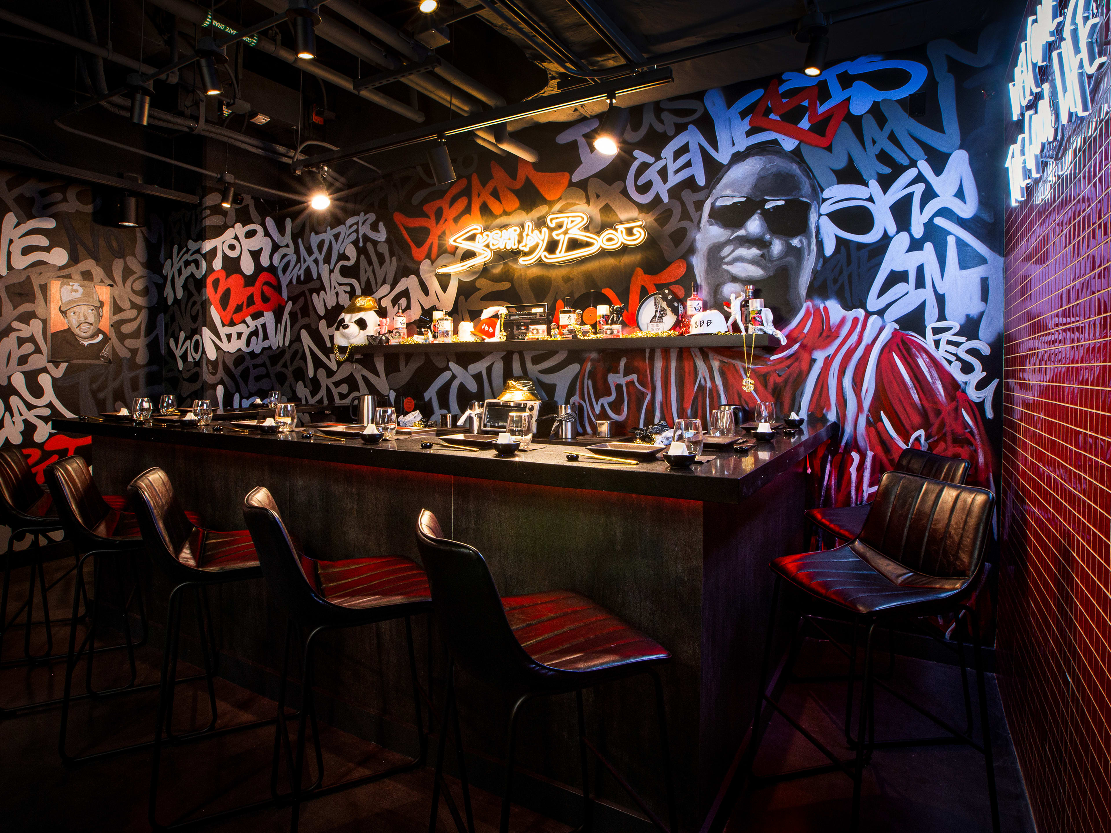 Small sushi bar set against a wall of graffiti and a mural of of Biggie