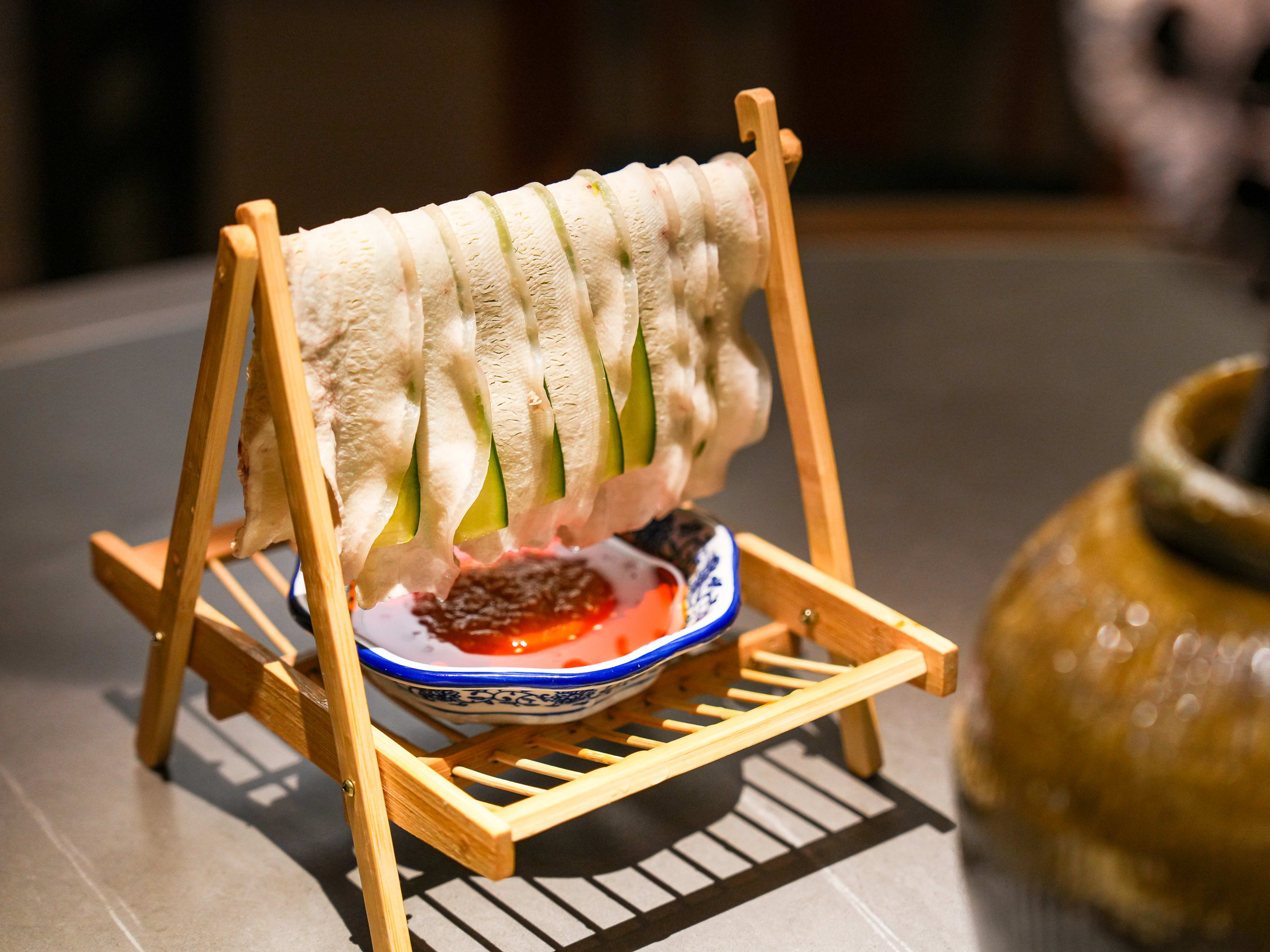 Swing pork belly with slivers of cucumber hung on wooden stand at Szechuan Mountain House