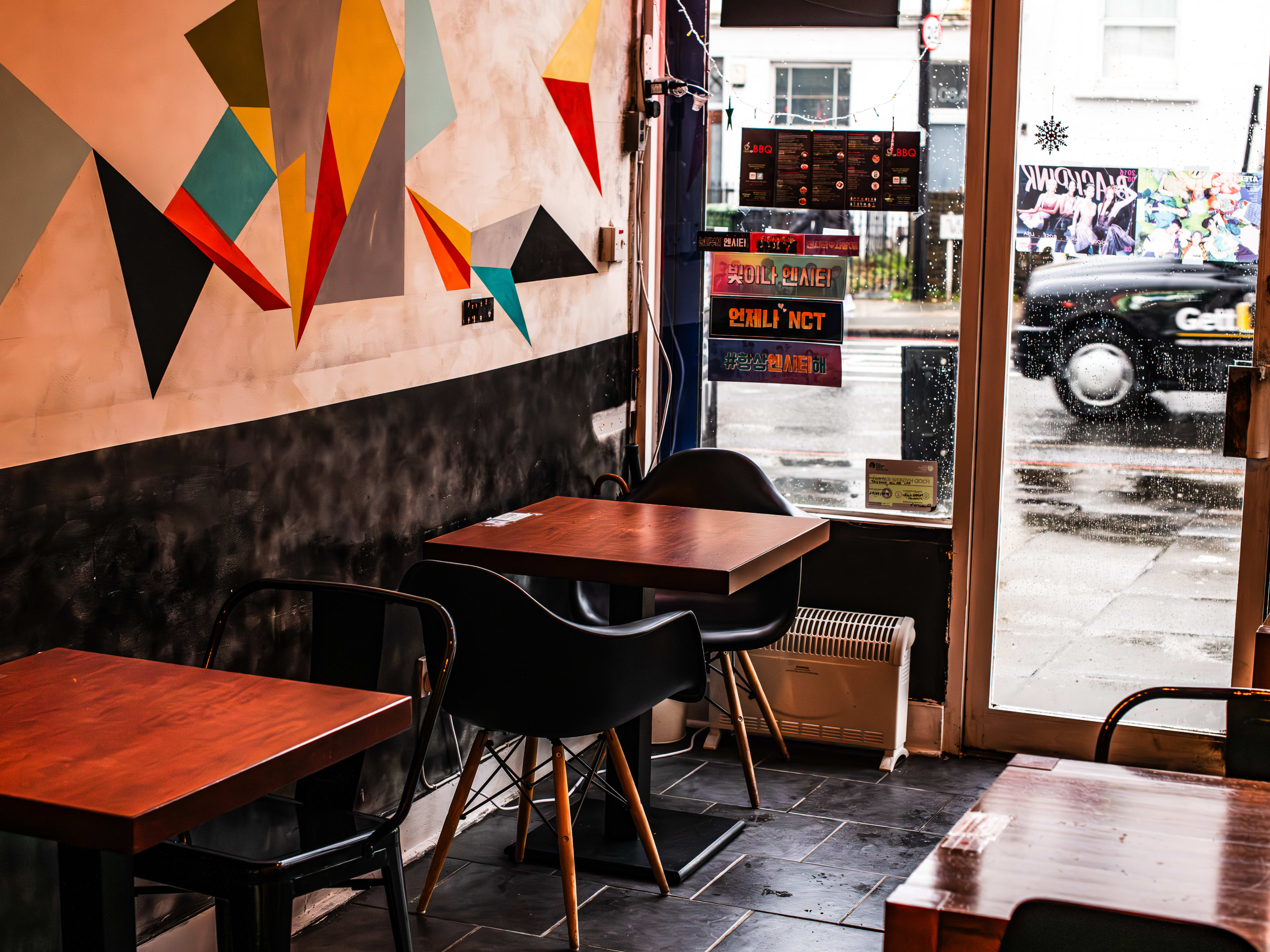 The interior of Taeyang Pocha with an abstract mural on the wall and wooden tables with black mod chairs