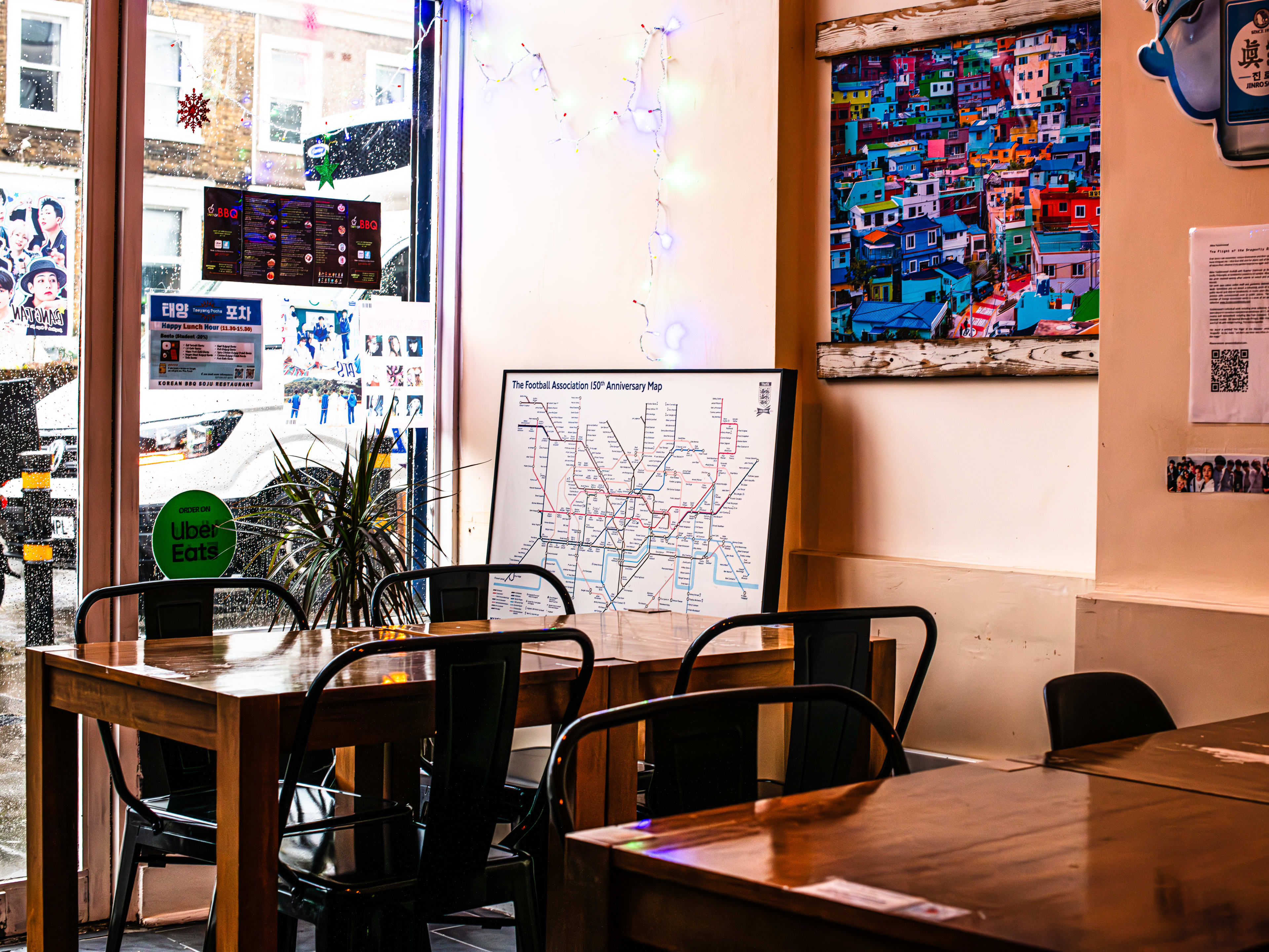 Interior of Taeyang Pocha with wooden tables, metal chairs, and art depicting maps on the wall