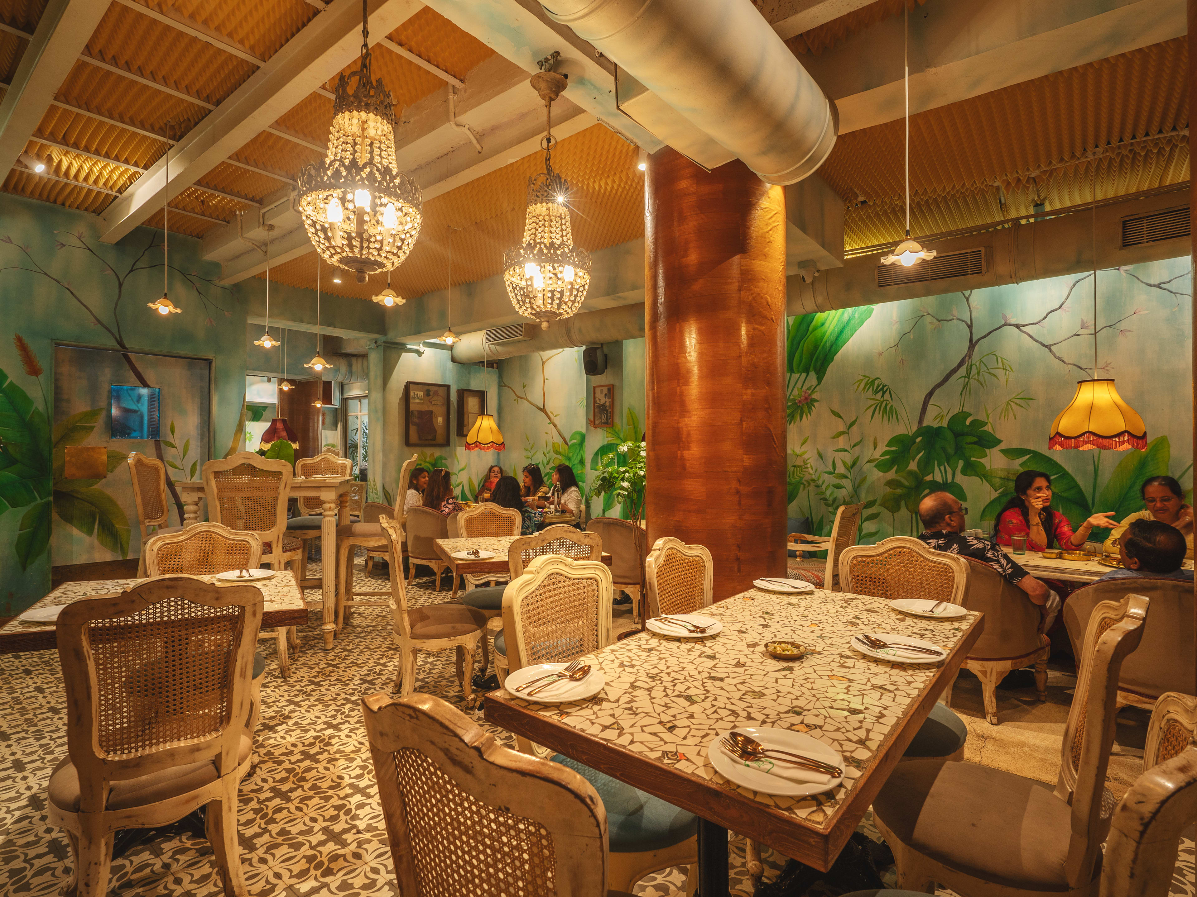 The Tanjore Tiffin Room's interior dining room with glowing chandeliers.