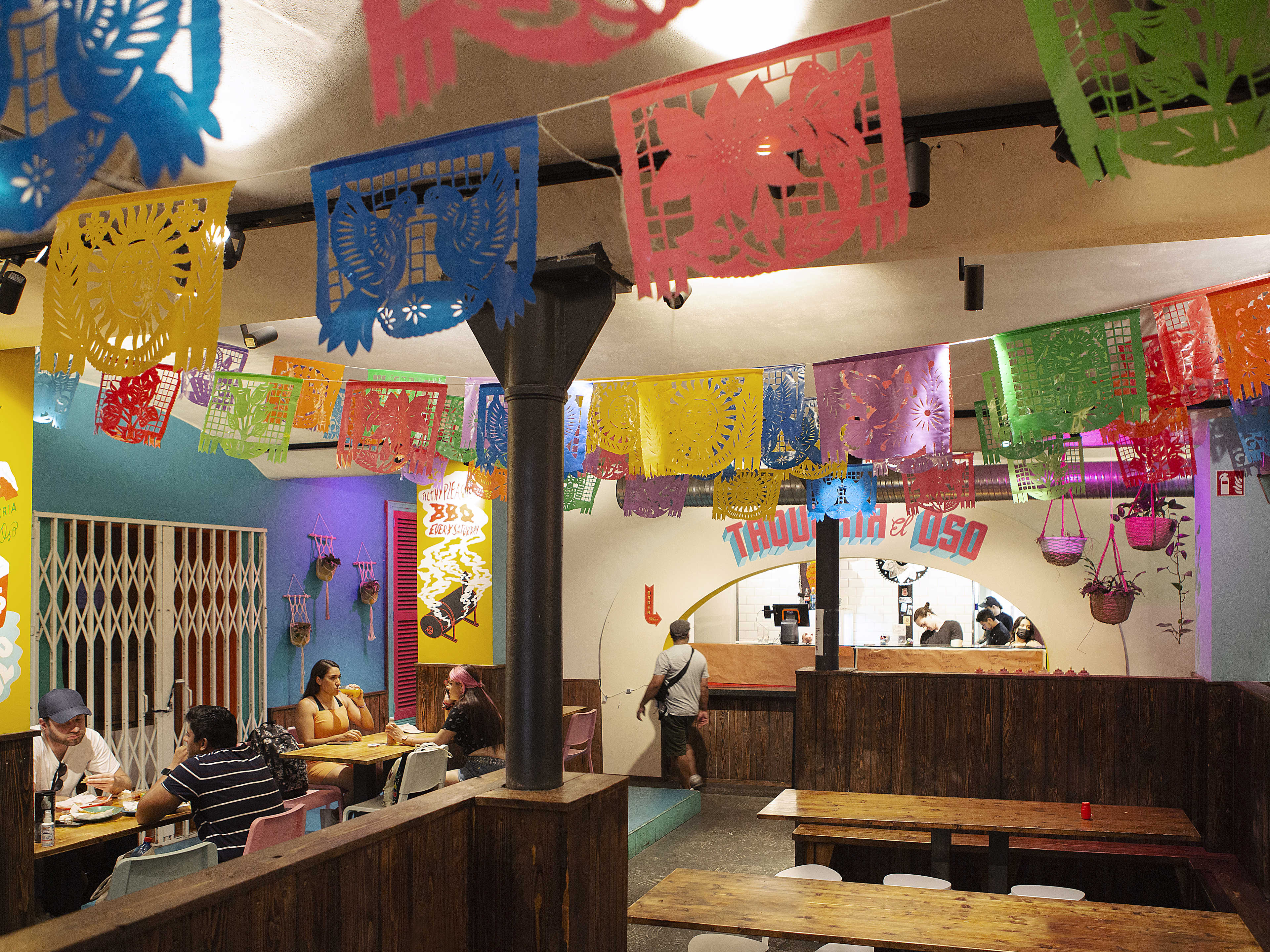 Interior dining space at Taqueria El Oso with colorful flags