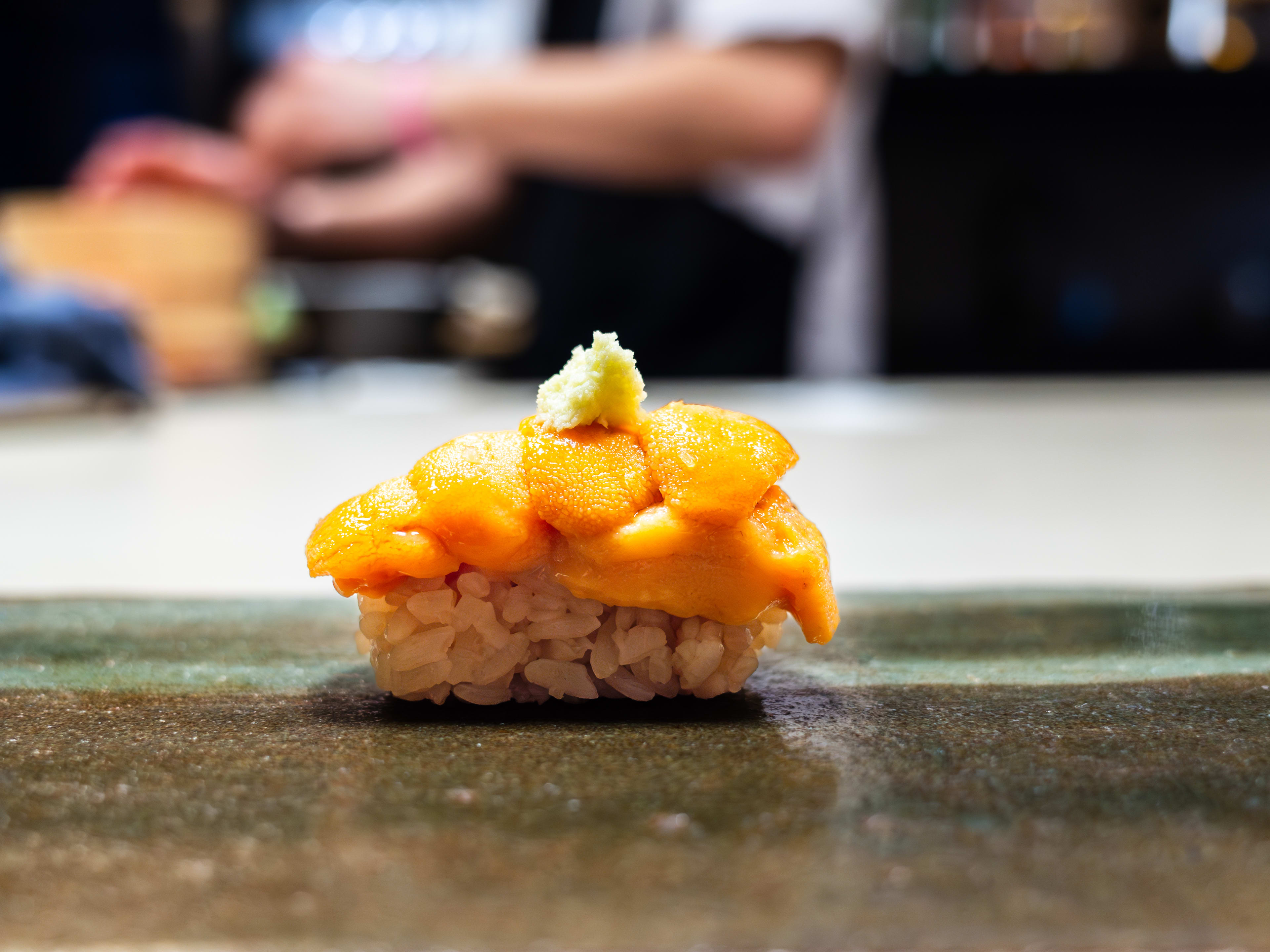 A piece of nigiri with uni and wasabi