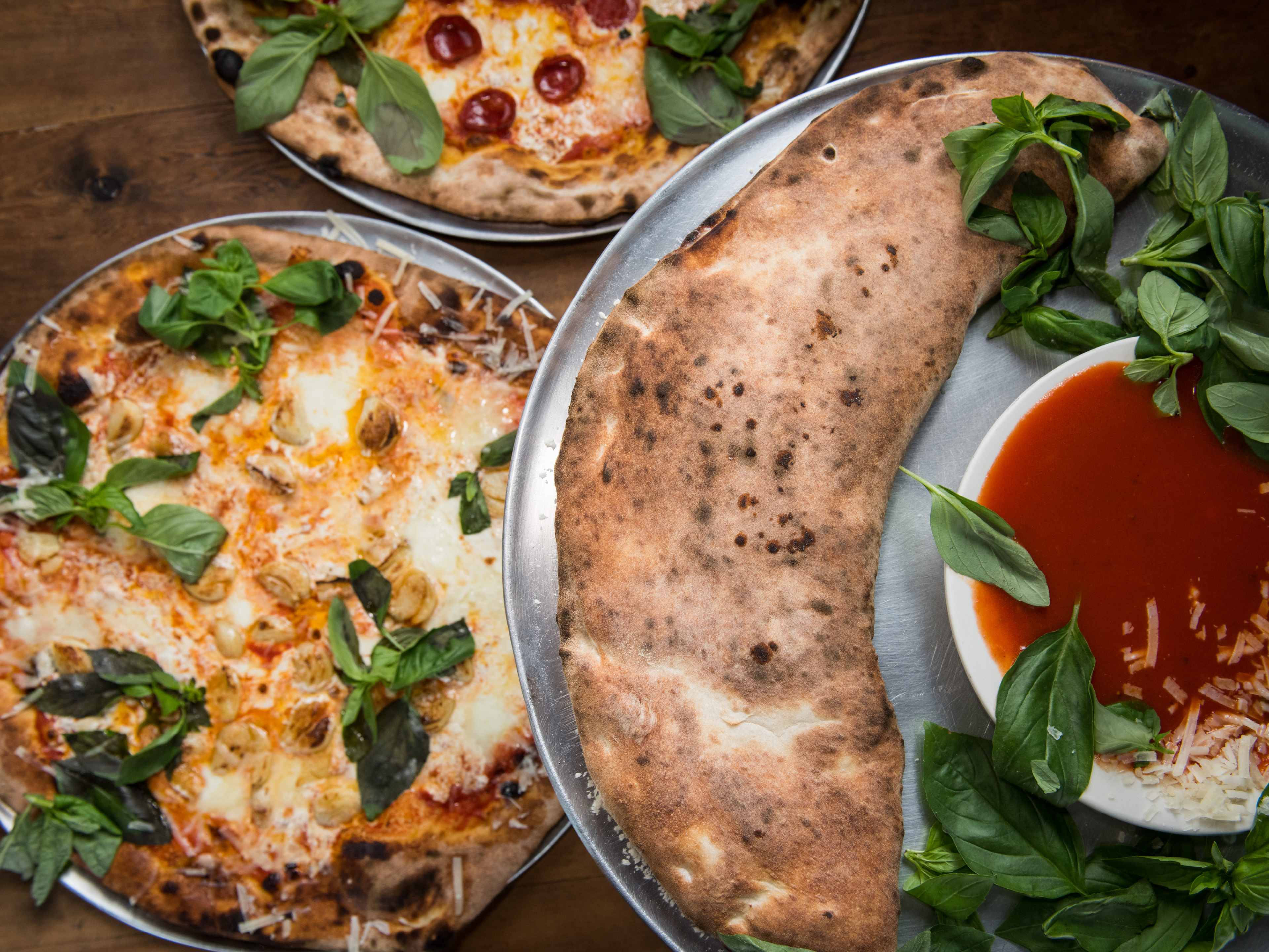 A spread of pizzas and a calzone from Lucali.